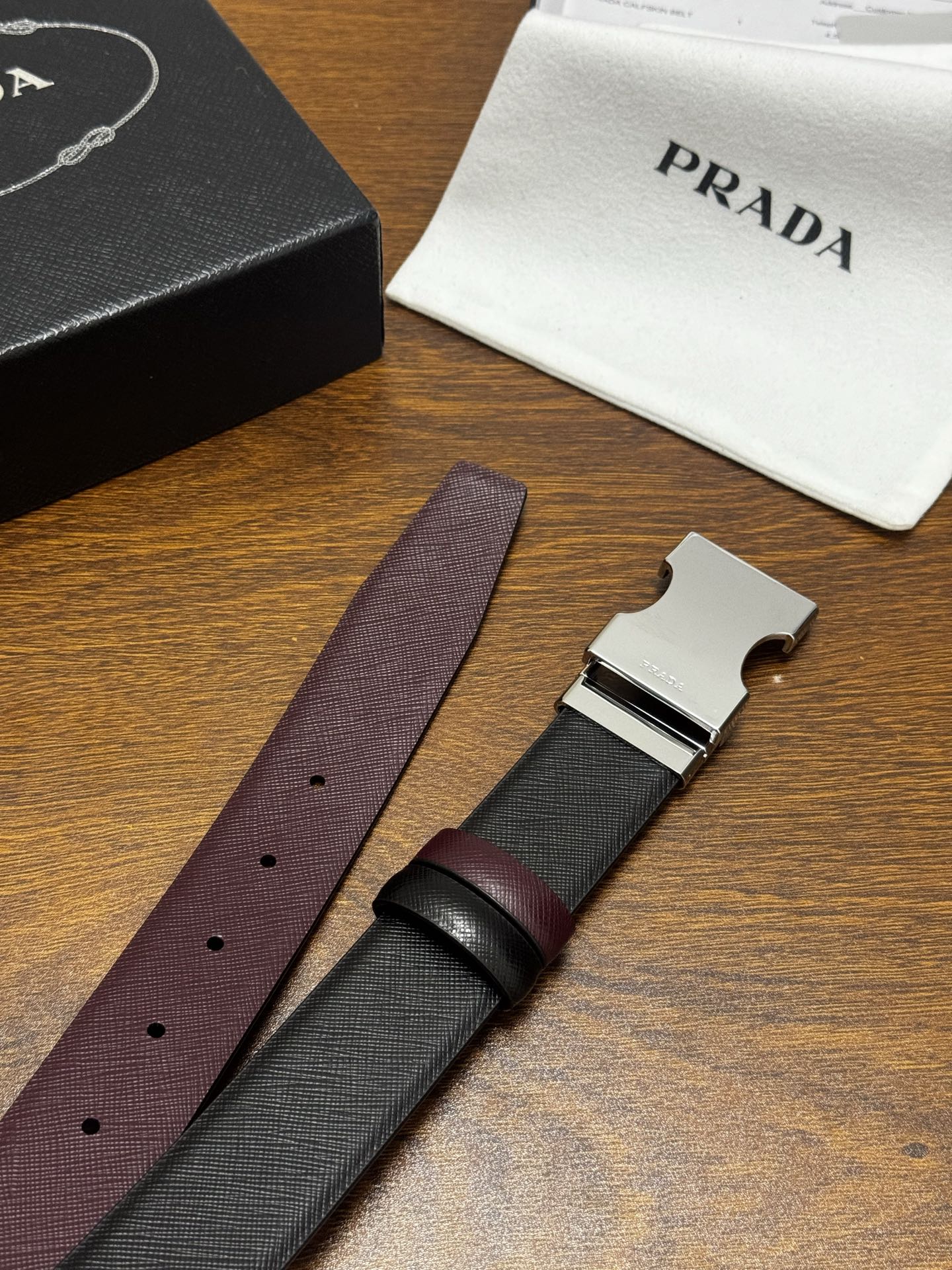 PRADA   3.5cm     黑/枣红   亮银扣 十字纹牛皮革腰带设计简约精致，亮眼的金属铜质工艺扣头。柔软自然