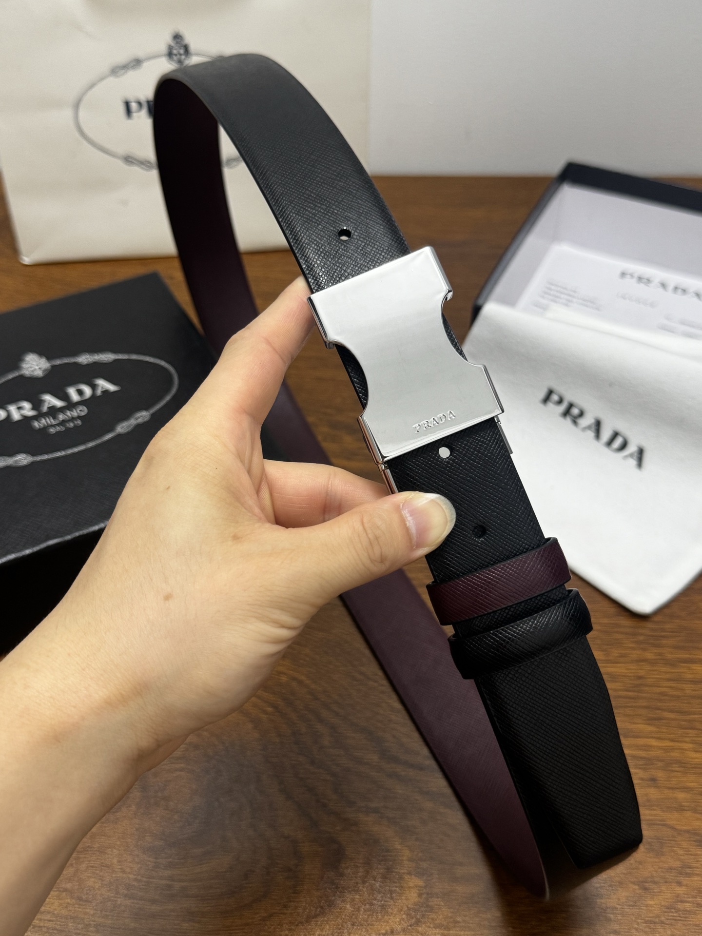 PRADA   3.5cm     黑/枣红   亮银扣 十字纹牛皮革腰带设计简约精致，亮眼的金属铜质工艺扣头。柔软自然