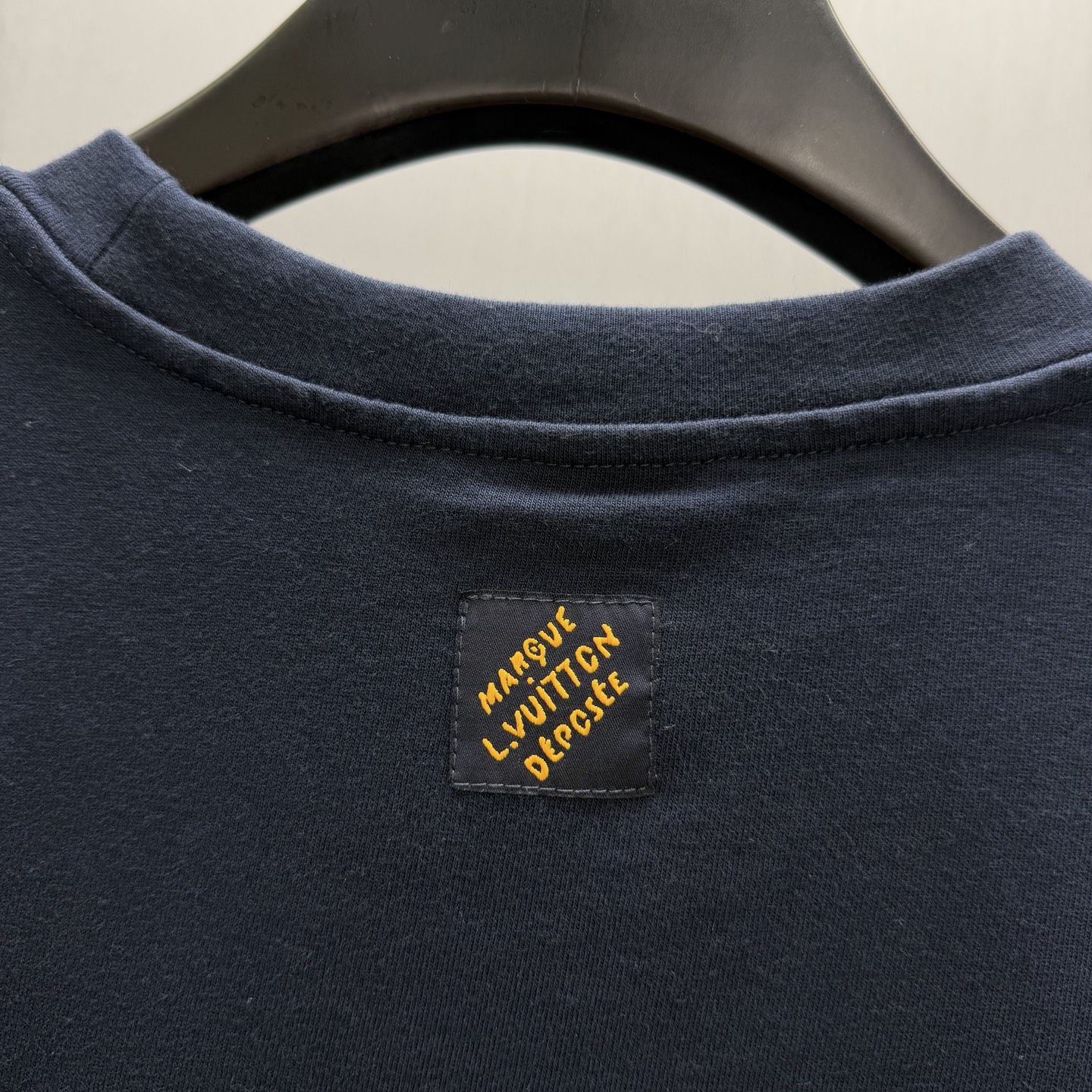 Louis Vuitton 这款 的蓝色 T 恤融入了独特的标志性设计——胸前饰有草书字体的丹宁路易威登贴饰