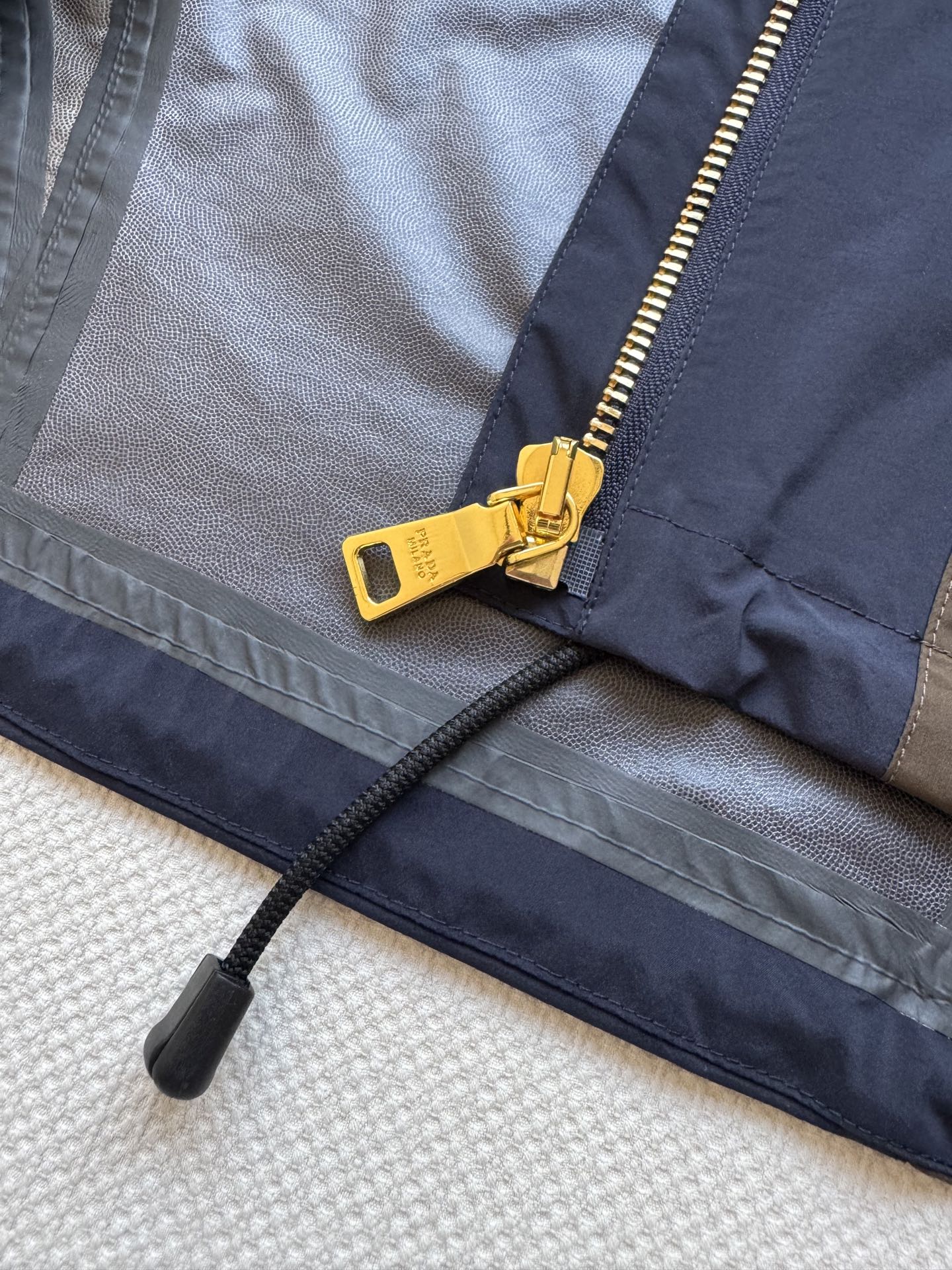 Prad*🆕2025SS早秋新款 撞色连帽冲锋外套 这款外套的配色设计超有巧思，棕色与深蓝色的拼接，就像