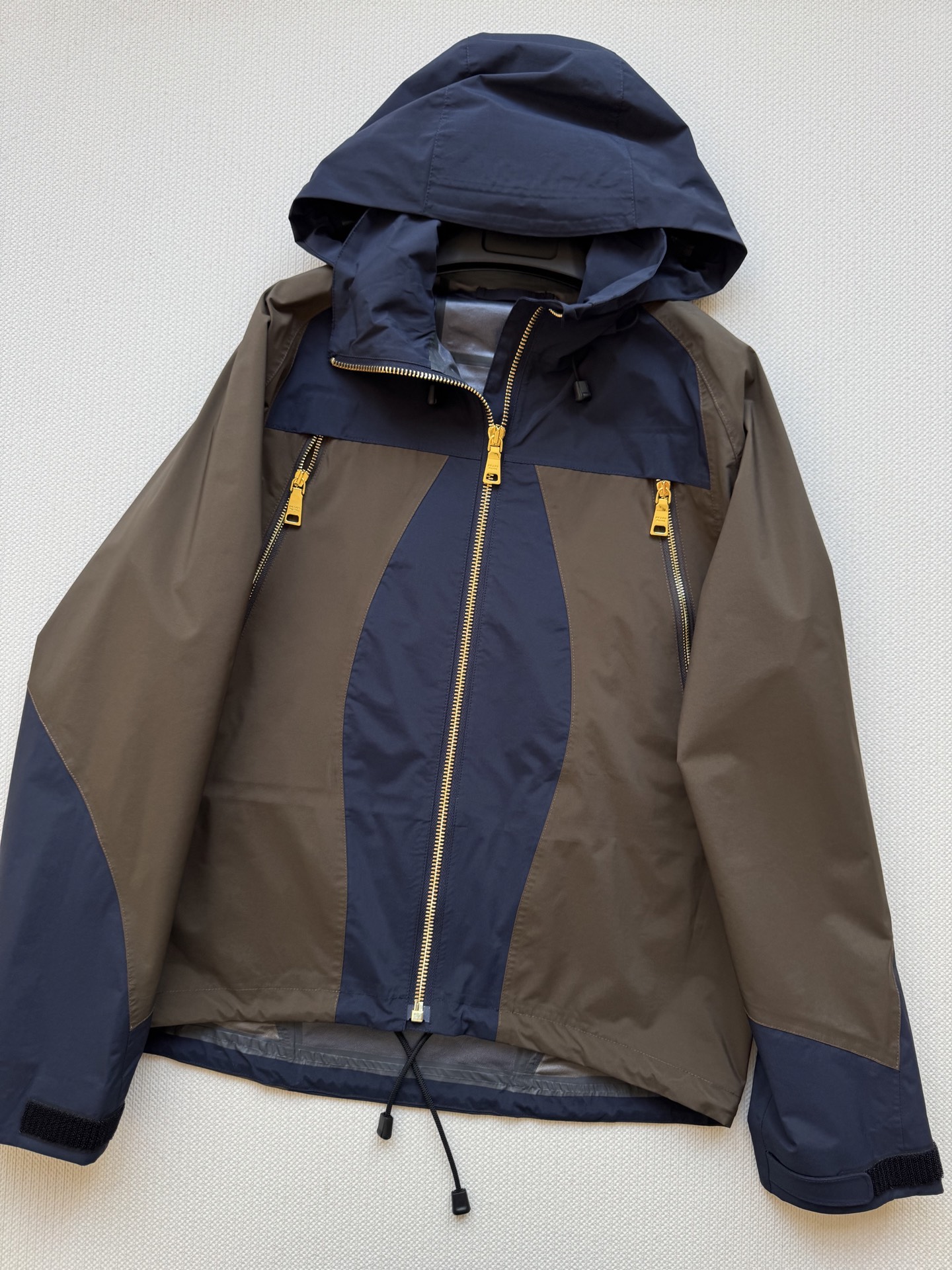 Prad*🆕2025SS早秋新款 撞色连帽冲锋外套 这款外套的配色设计超有巧思，棕色与深蓝色的拼接，就像