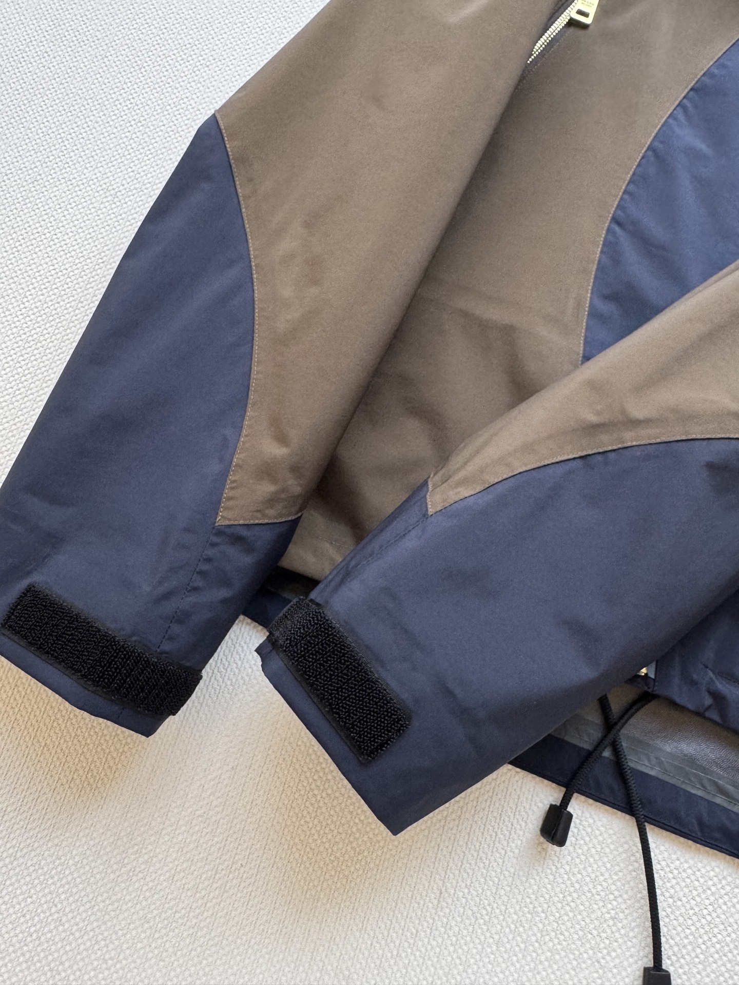 Prad*🆕2025SS早秋新款 撞色连帽冲锋外套 这款外套的配色设计超有巧思，棕色与深蓝色的拼接，就像