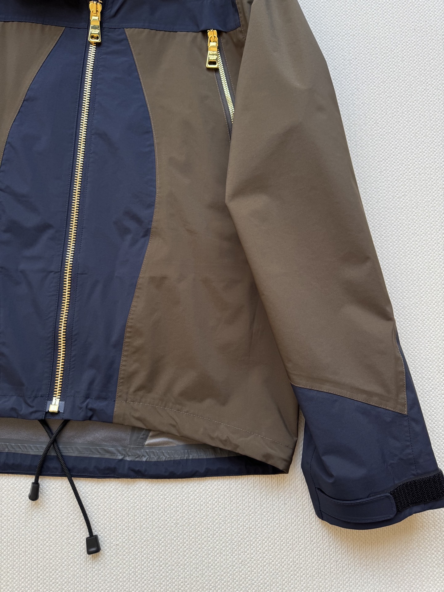 Prad*🆕2025SS早秋新款 撞色连帽冲锋外套 这款外套的配色设计超有巧思，棕色与深蓝色的拼接，就像