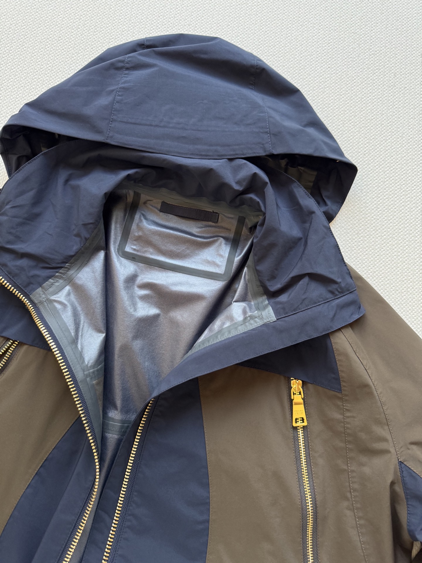 Prad*🆕2025SS早秋新款 撞色连帽冲锋外套 这款外套的配色设计超有巧思，棕色与深蓝色的拼接，就像