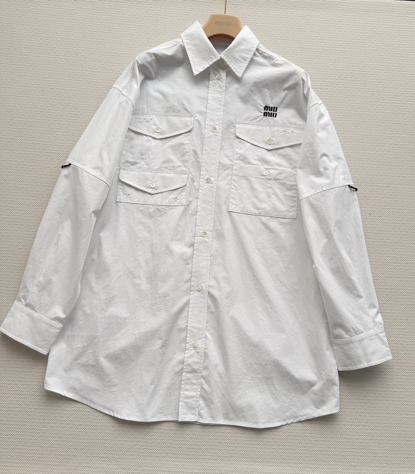 MiuMi*🆕这款白色工装风衬衫，采用全棉材质，挺括有型，胸前双口袋+袖口抽绳设计，机能感满满✨。左胸“