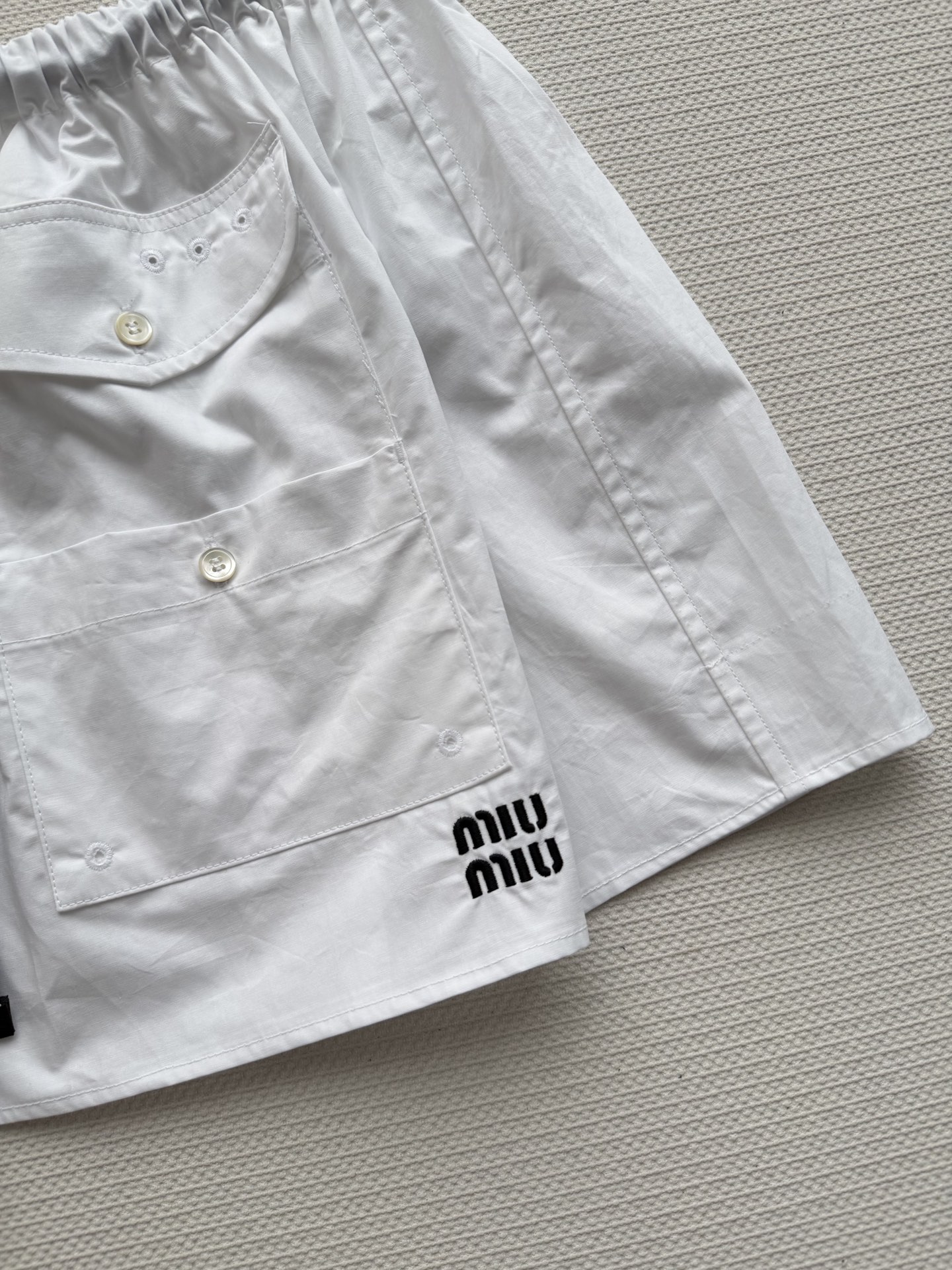 Miu Mi*🆕这款白色工装半裙，采用轻薄科技府绸，触感柔软又挺括。A字版型+松紧腰，舒适显瘦，适合多种