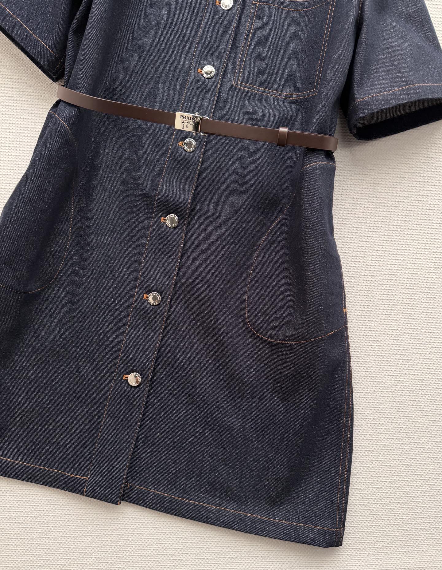 PRAD*🆕这款深色牛仔连衣裙，经典衬衫式设计，短袖+单排扣，简约又有细节感✨。腰部可调节腰带，轻松勾勒
