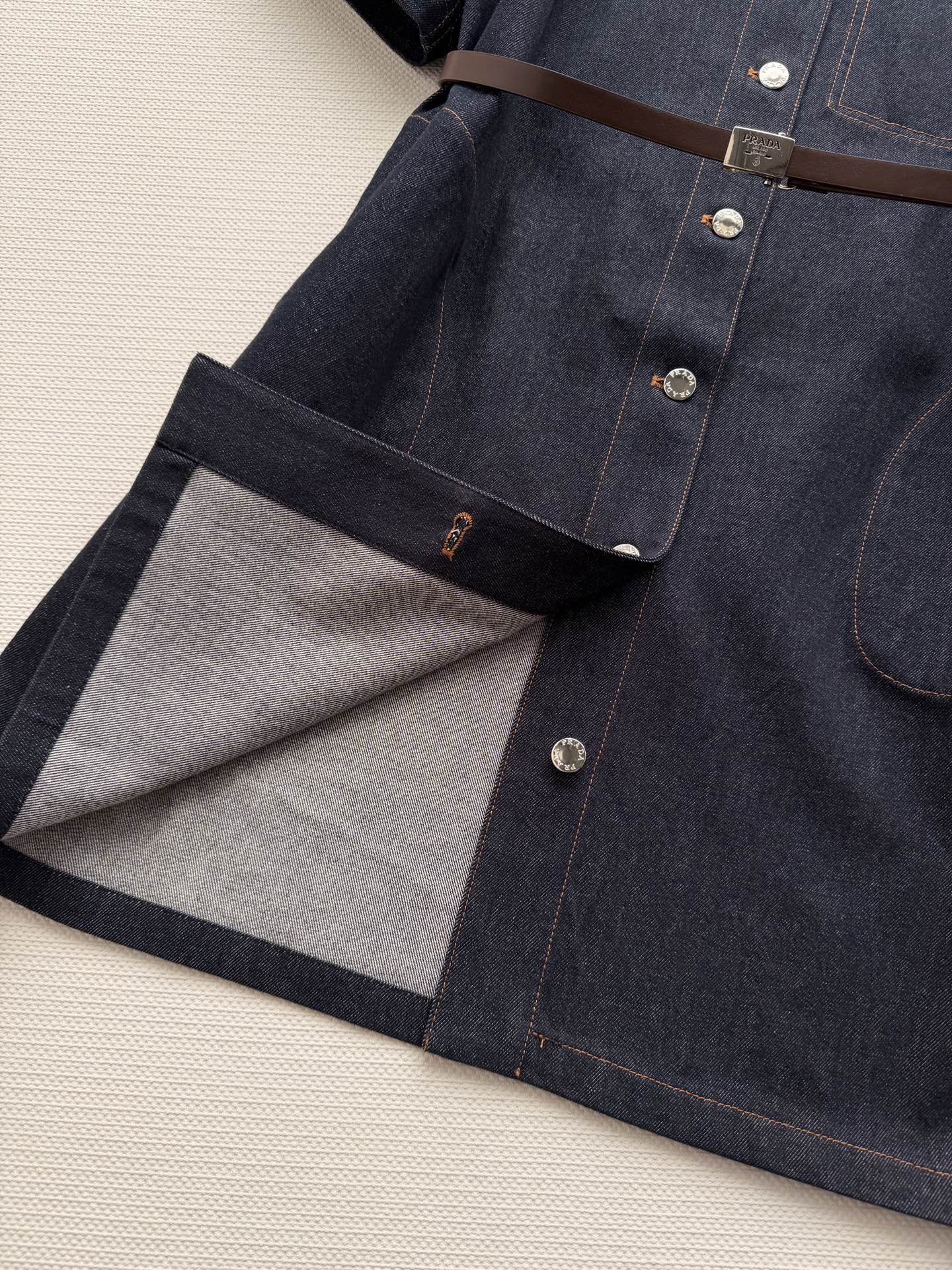PRAD*🆕这款深色牛仔连衣裙，经典衬衫式设计，短袖+单排扣，简约又有细节感✨。腰部可调节腰带，轻松勾勒
