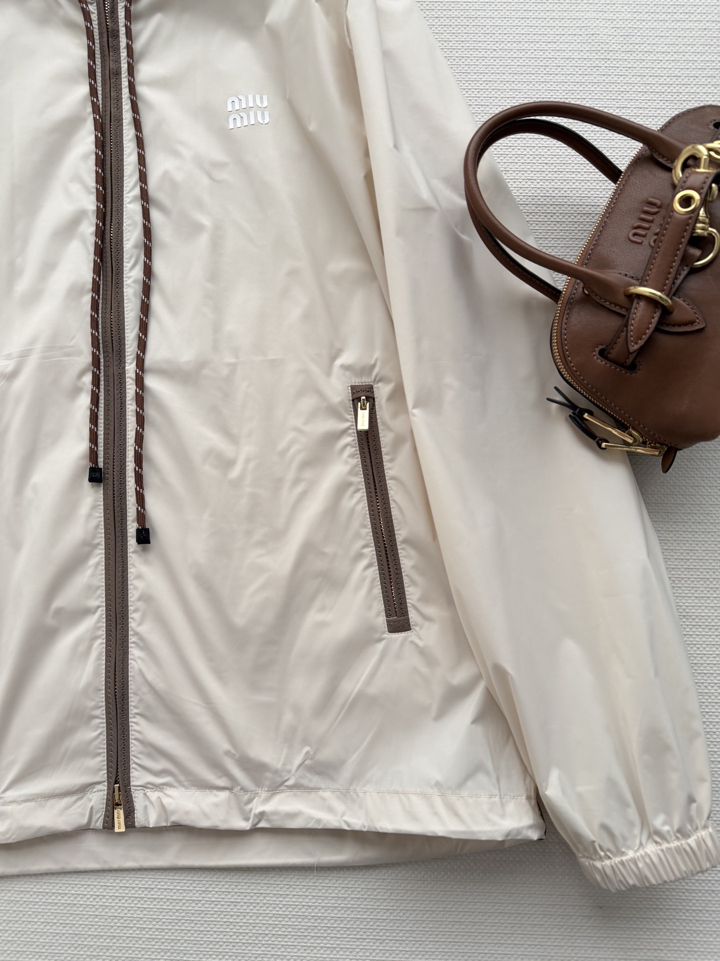 Miumi*🆕徽标字母宽松尼龙连帽外套 定制环保再生尼龙材质，质感自带丝绸光泽，穿搭有型，整体以素色为基