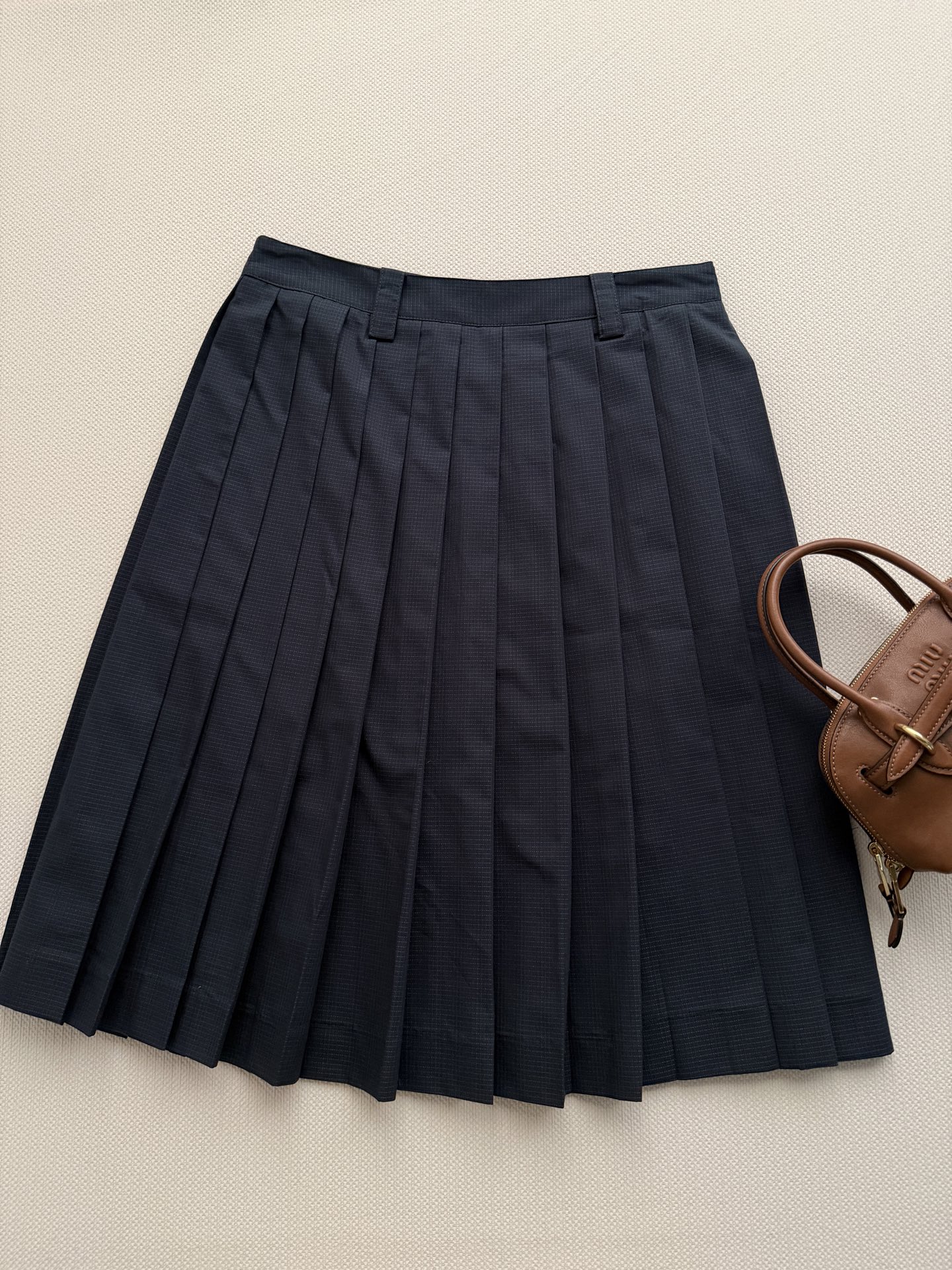 miumi*🆕 这款精致的褶皱半身裙采用棉质防撕裂面料制成，轻盈的技术质感中流露运动风格，展现女性化的轮