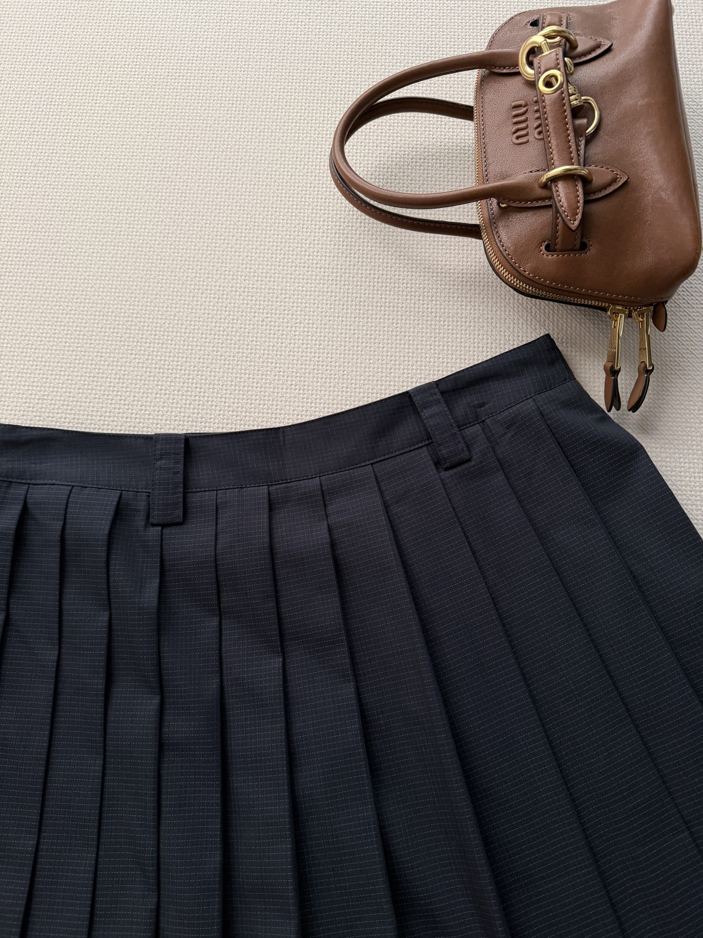 miumi*🆕 这款精致的褶皱半身裙采用棉质防撕裂面料制成，轻盈的技术质感中流露运动风格，展现女性化的轮