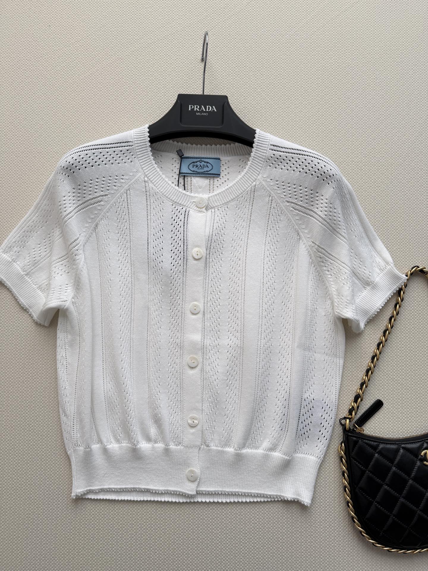 Prada🆕26s夏季新款白色针织开衫，采用轻薄透气针织面料，镂空花纹设计超有层次感✨。短袖+圆领+珍珠