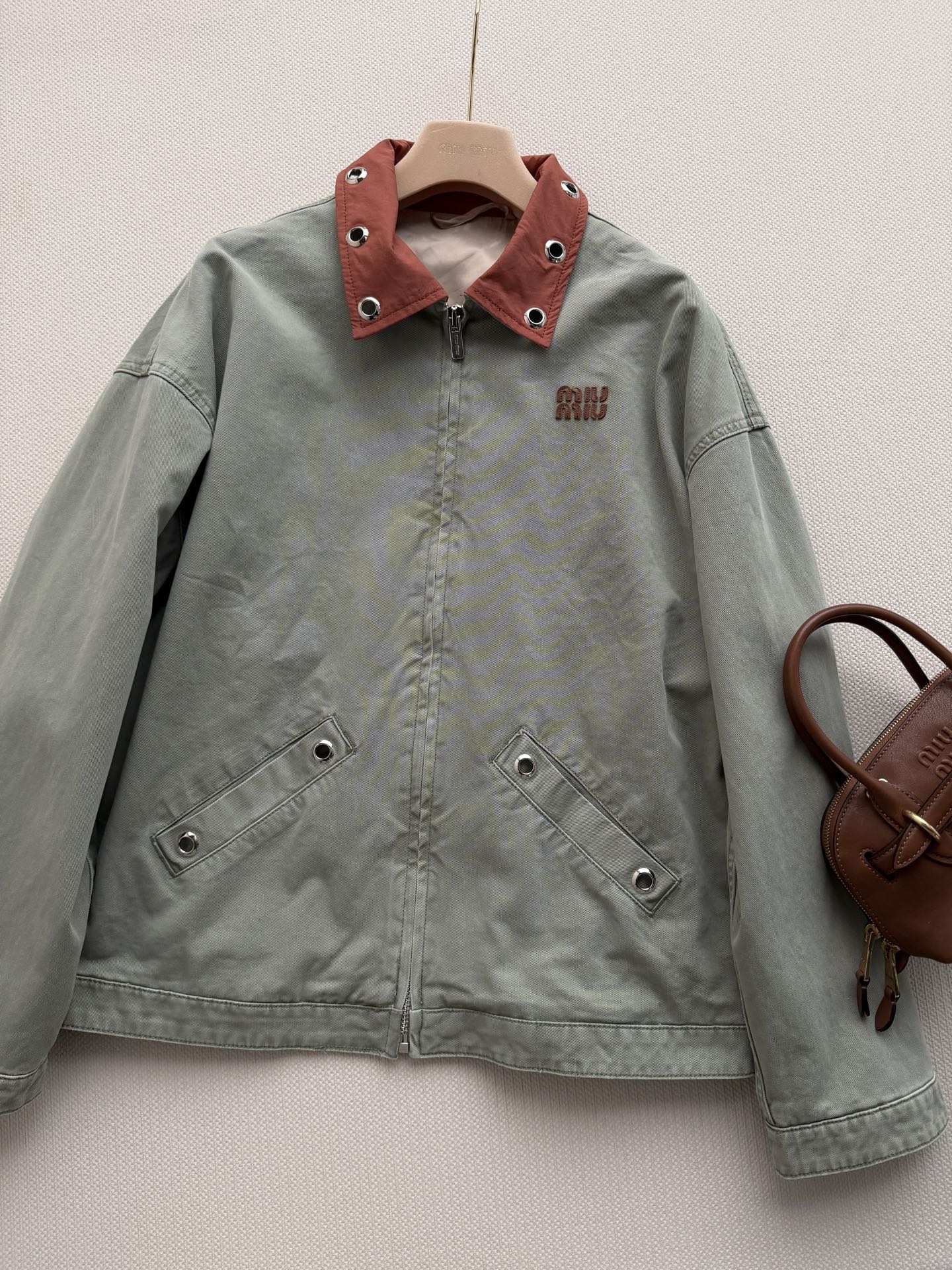 Miu Mi*🆕26春夏秀场新品复古牛仔外套 这件灰绿色夹克以出人意料的橘色金属领子点睛，冷冽与炽烈在领