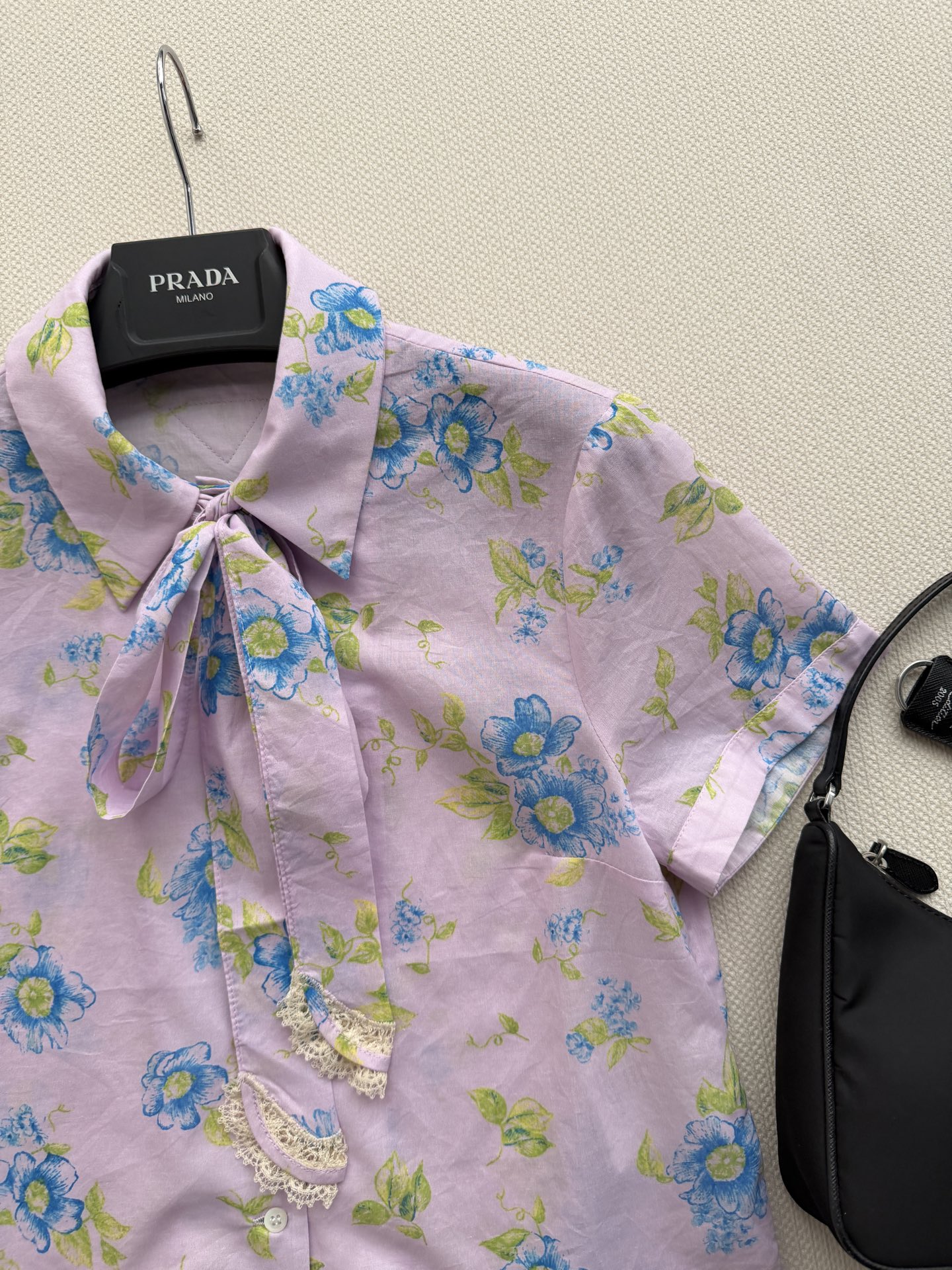 Prad*浅粉底色花卉印花短袖衬衫 蓝绿花卉图案清新柔和，春日氛围感满满。领口蝴蝶结+蕾丝边设计，少女感十足✨。轻薄透气