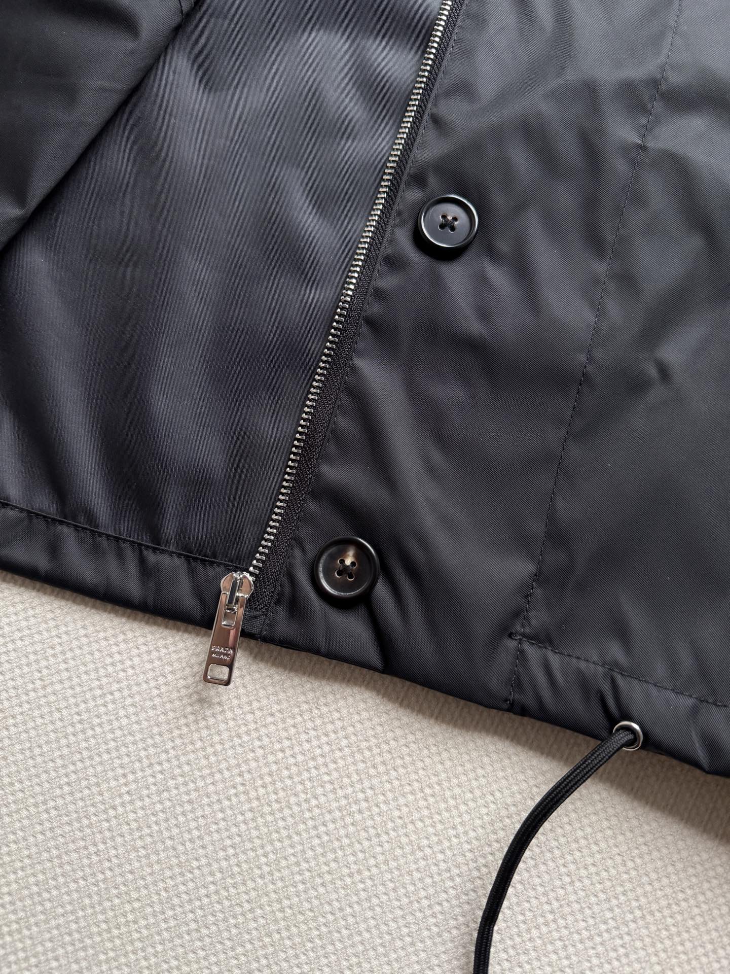 Prad*🆕 26早秋系列的圆领再生尼龙夹克​​，胸前有经典的三角珐琅徽标，下摆带抽绳收口设计，整体版型偏短款、微宽松。