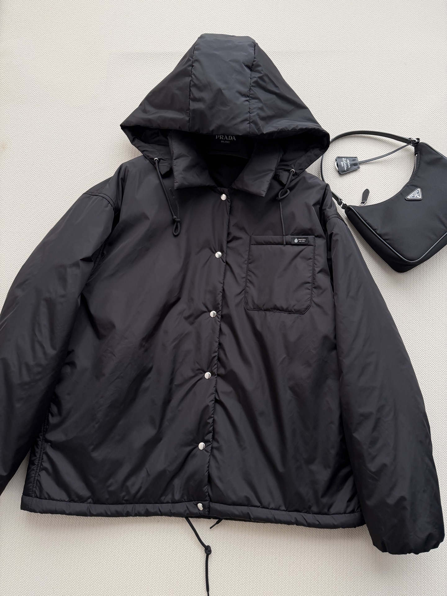 Prad*🆕这款短夹克以极简方式诠释实用机能，采用轻盈Re-Nylon（再生尼龙）面料打造，设计利落流畅。此款造型以轻盈