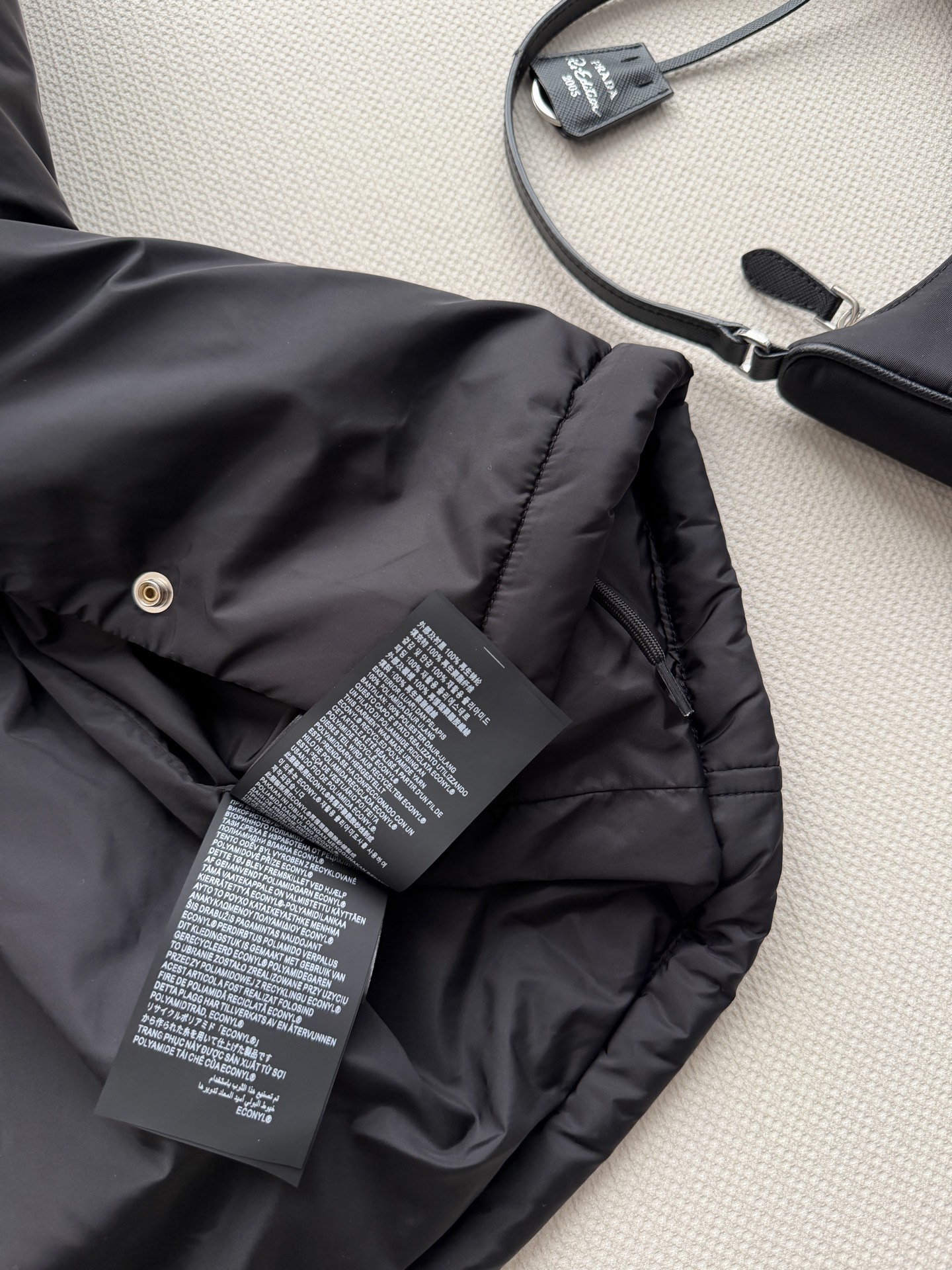 Prad*🆕这款短夹克以极简方式诠释实用机能，采用轻盈Re-Nylon（再生尼龙）面料打造，设计利落流畅。此款造型以轻盈