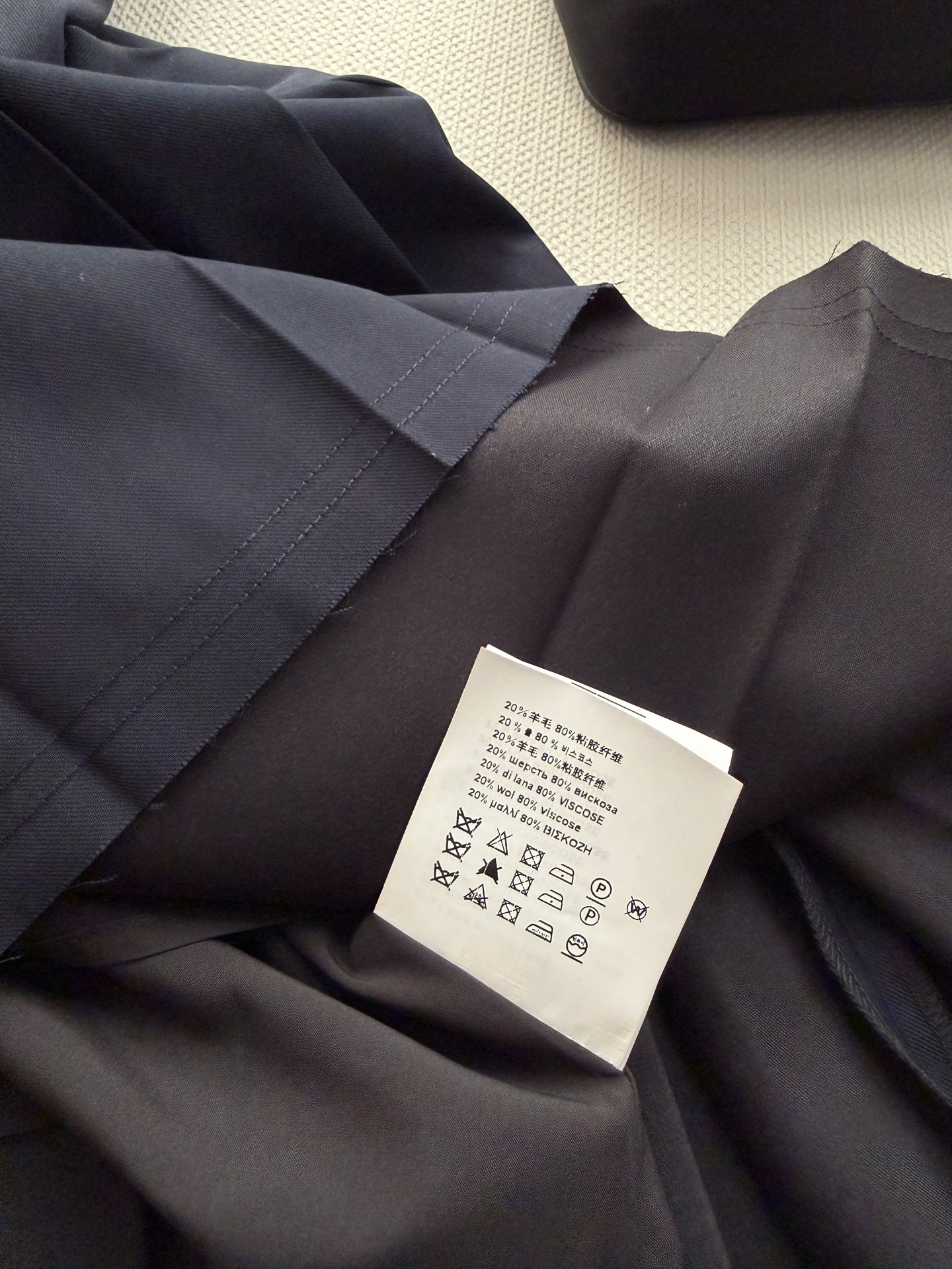 Prad*🆕细密褶裥从腰头一直垂到裙摆，A字廓形，长度到小腿中段。黑色皮质腰带配银色金属环扣，侧面挂了一个小巧的黑色 P