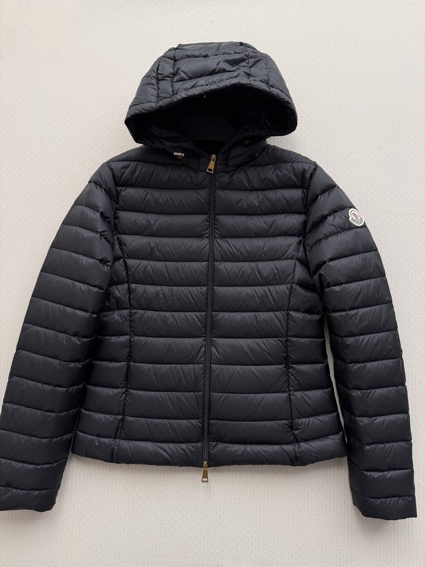 Moncle*🆕排骨款羽绒服，细密横向绗缝，轻薄贴身不臃肿。连帽设计，前襟拉链开合，金色拉链头做点缀。左臂有经典的 Mo