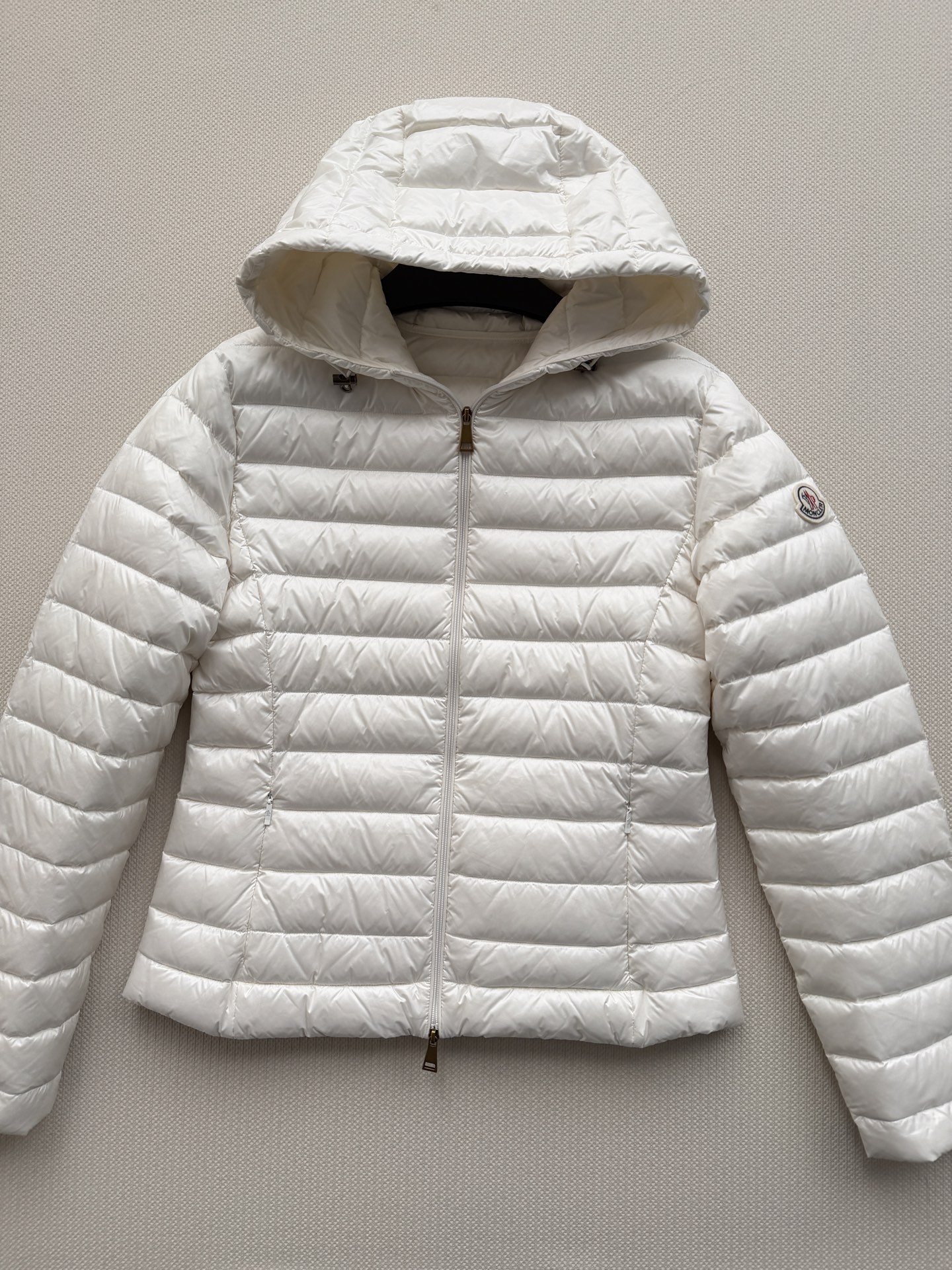 Moncle*🆕排骨款羽绒服，细密横向绗缝，轻薄贴身不臃肿。连帽设计，前襟拉链开合，金色拉链头做点缀。左臂有经典的 Mo