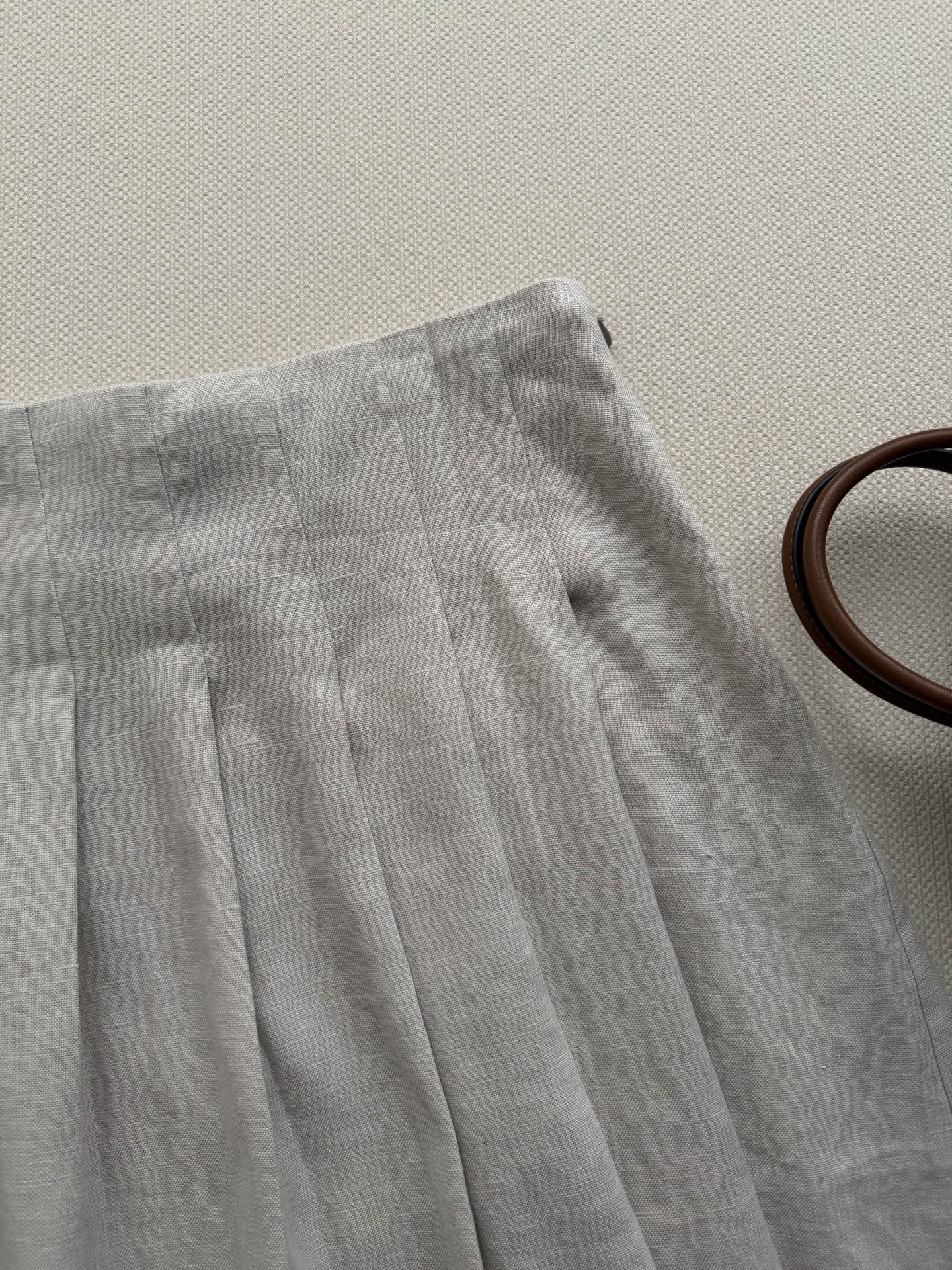 miumi*🆕新品亚麻百褶半身裙 采用柔软亚麻面料制成 背面饰有品牌标识刺绣 经典A字版型  腰部松紧抽绳设计 侧面拉链