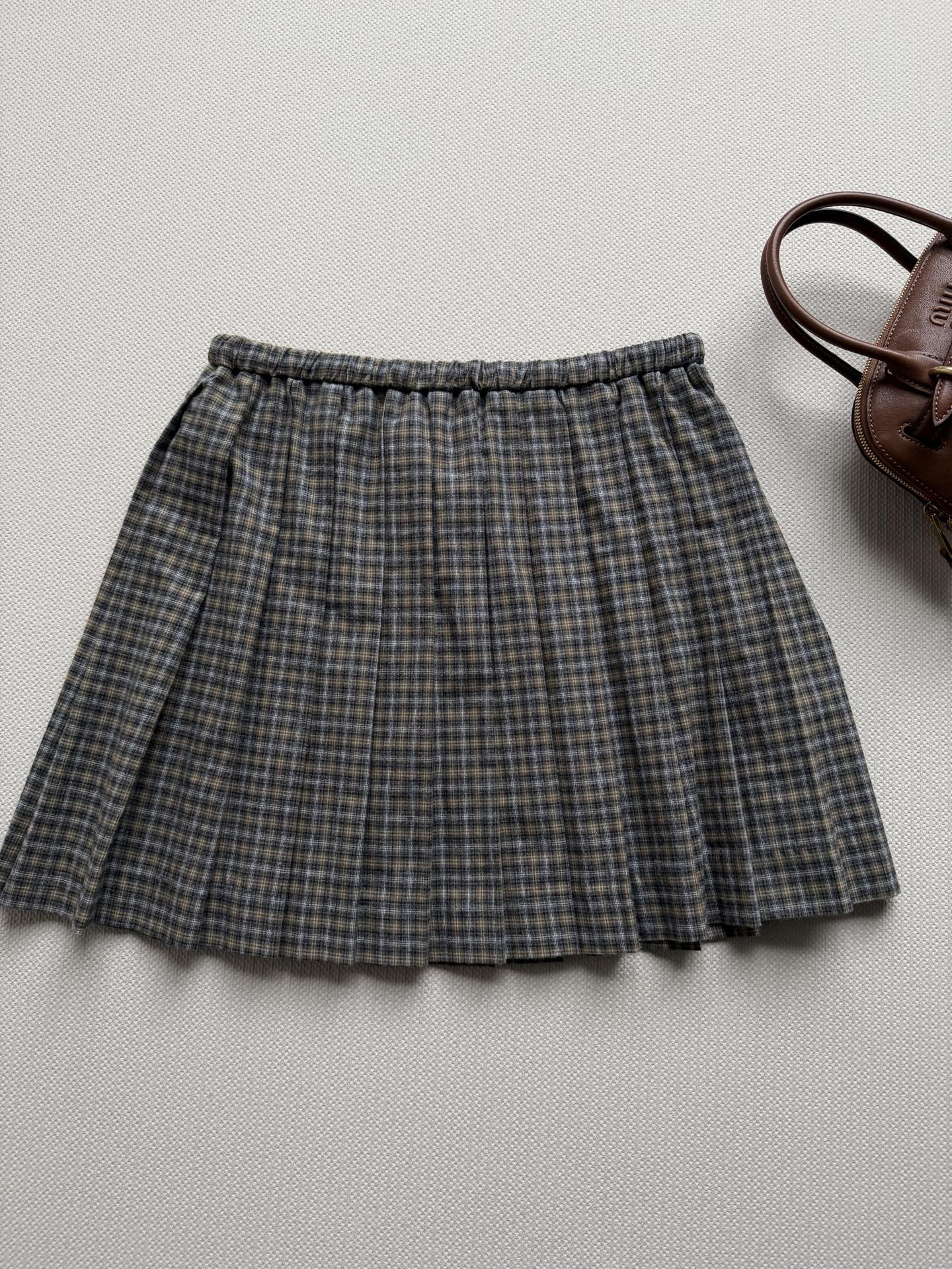 miumi*🆕褶饰细节勾勒这款格纹法兰绒迷你半身裙，灵感源自女装风格准则。撞色运动细节为整体设计画龙点睛，呈现当代学院风