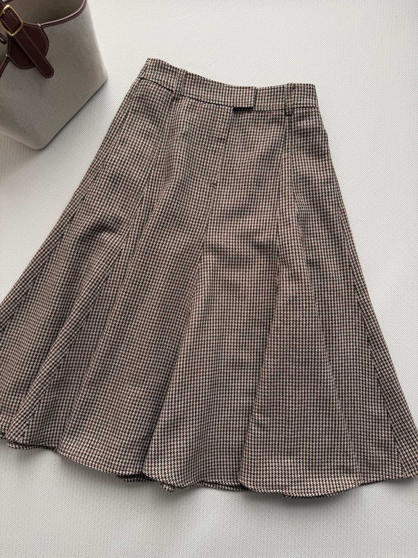 Brunello Cucinelli 🆕系列的珍贵材料重新诠释了这款初剪羊毛闪烁千鸟格半裙，经典鱼尾的熠熠生辉衬托下，营