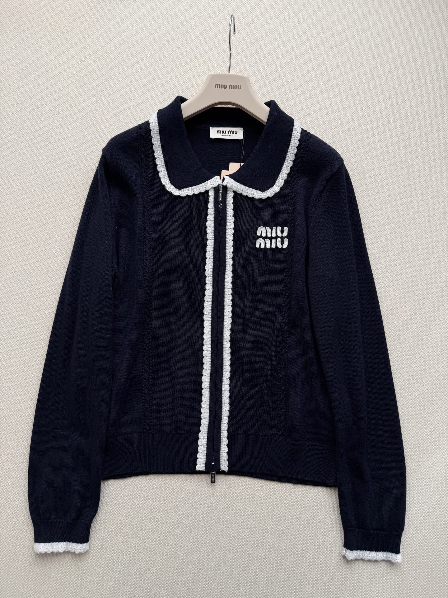 miumi*🆕质地紧密有弹性。翻领设计，领口、门襟和袖口都有白色的粗线滚边装饰，形成强烈的撞色效果。前襟拉链开合。左胸有
