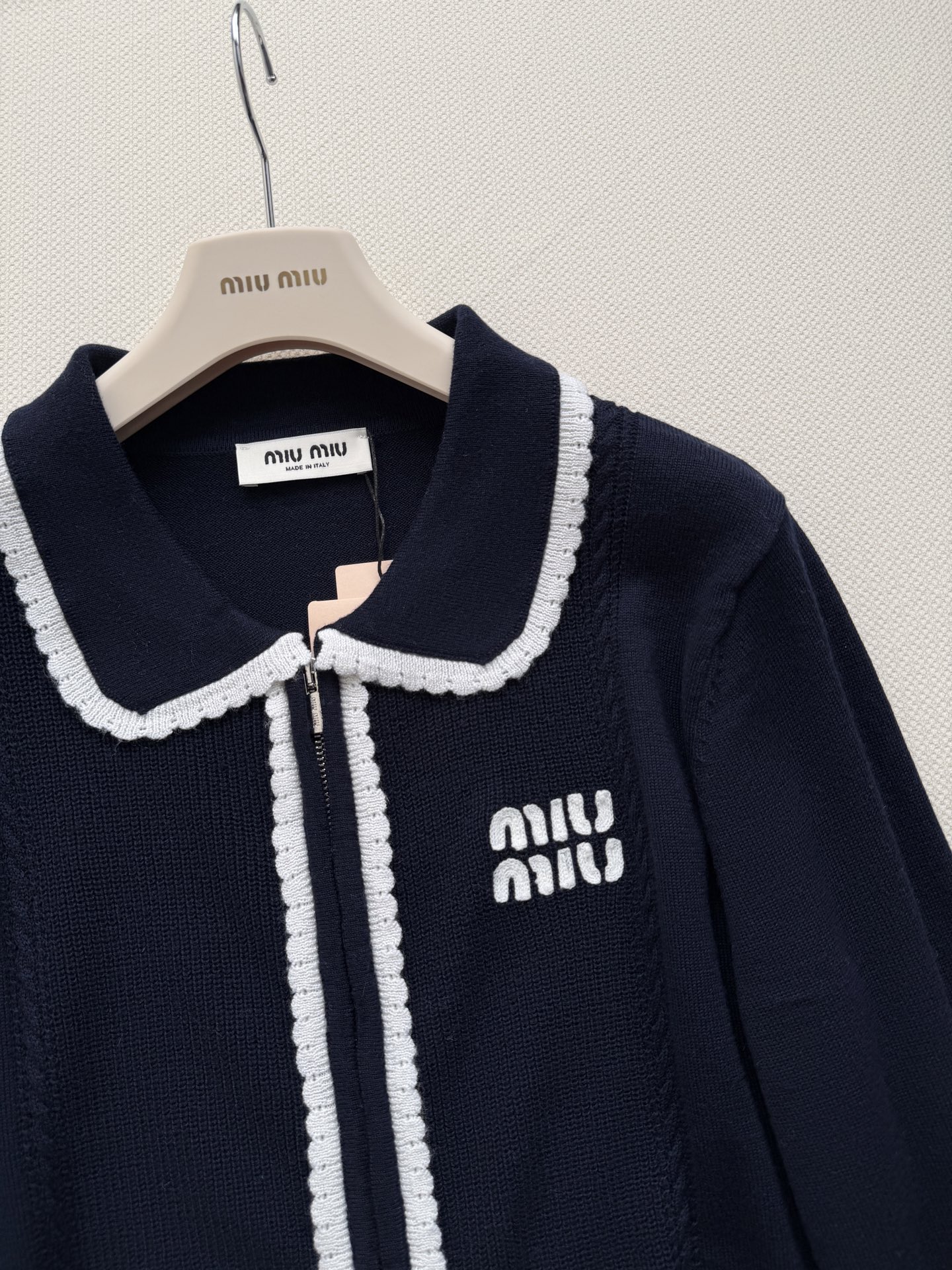 miumi*🆕质地紧密有弹性。翻领设计，领口、门襟和袖口都有白色的粗线滚边装饰，形成强烈的撞色效果。前襟拉链开合。左胸有