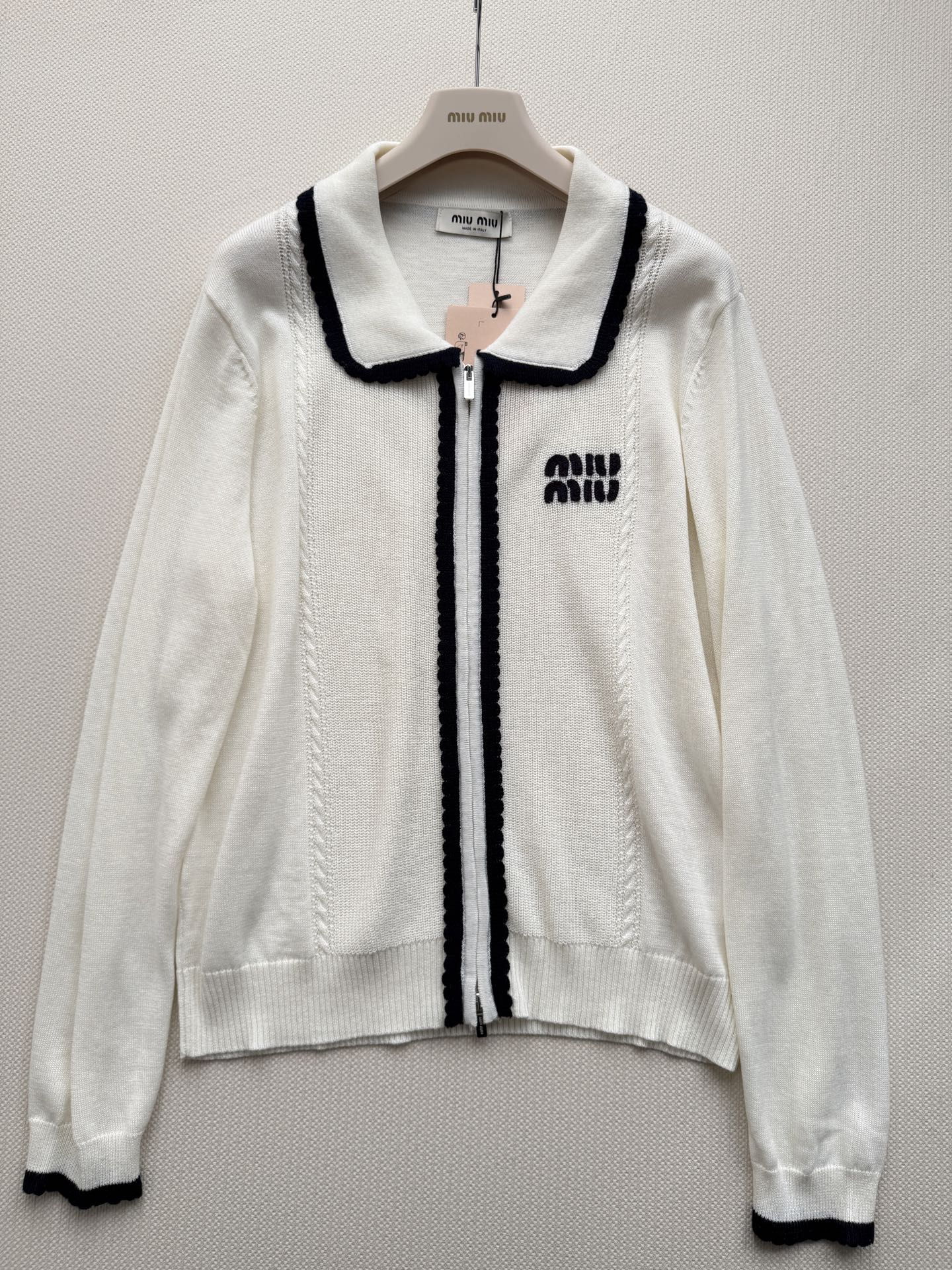 miumi*🆕质地紧密有弹性。翻领设计，领口、门襟和袖口都有白色的粗线滚边装饰，形成强烈的撞色效果。前襟拉链开合。左胸有
