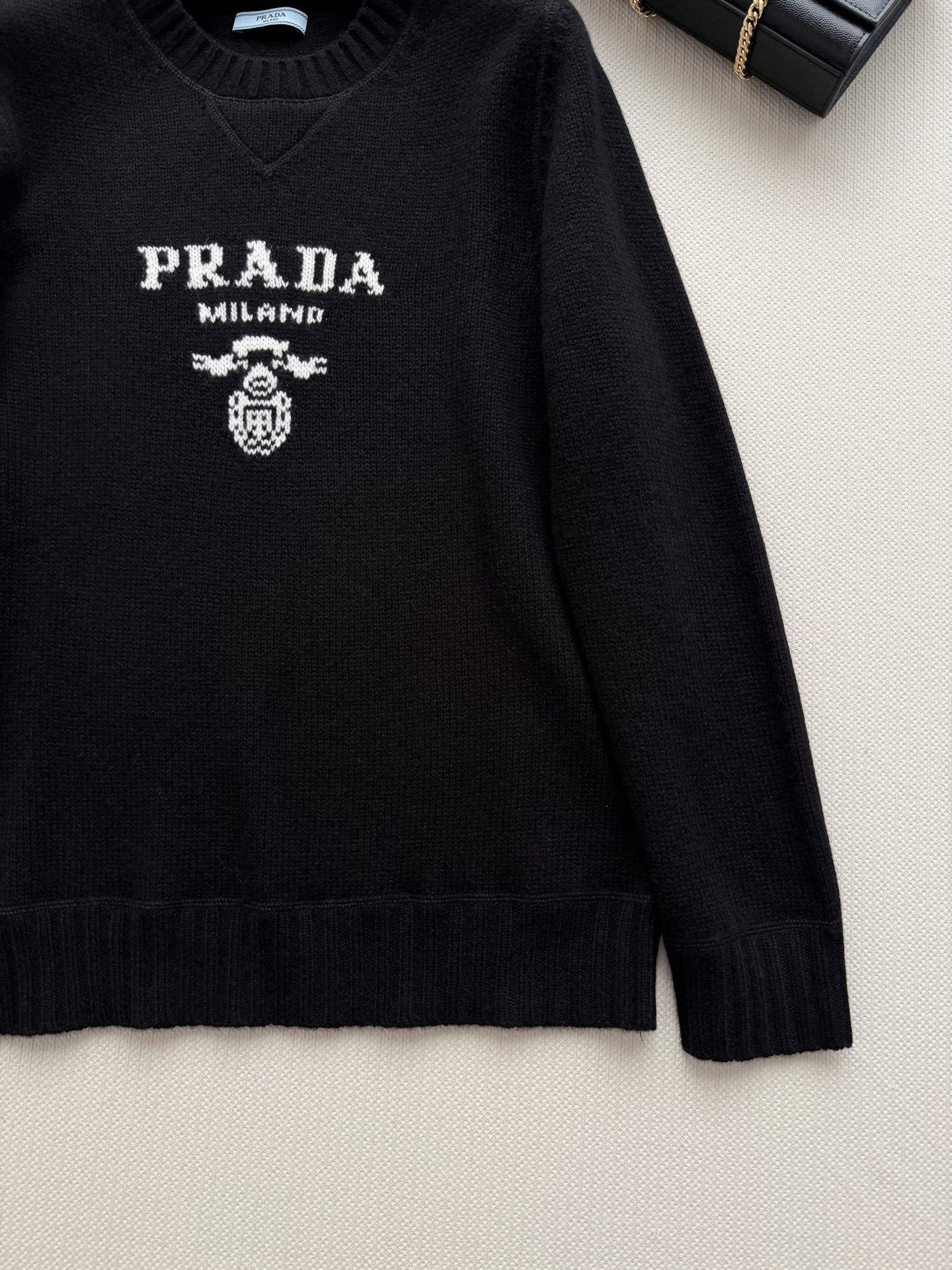 Prad*🆕细针编织，羊毛➕羊绒，质地细腻有微微的绒感。圆领设计，长袖，略宽松的廓形。胸口有 Prad*标志性的三角形徽