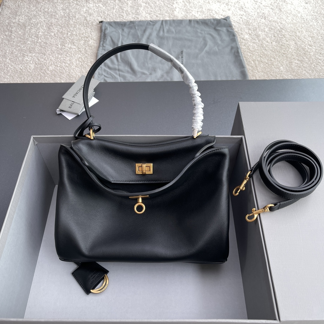 NO:198923,Original leather [top high-end ~ imported materials] RODEO small handbag uses imported original leather black smooth cowhide leather, decorated with old gold metal accessories, single handle height 18.5 cm, removable leather key ring, two buckle rings, rotary lock opening and closing, 1 main compartment, 1 internal zipper pocket, 2 back flat bags, side snap buckles, 4 brass feet guarding, imported sheepskin lining. No. 7897792 black full leather/gold buckle Specifications w28.9×h20×d9.9cm, Balenciaga, cowhide, sheepskin19860909原厂皮【顶级高端～进口材料】RODEO小號手提包 采用進口原廠皮黑色光滑牛皮革,飾以做舊金色金屬配件,單手柄高度18.5釐米,可拆缷皮革鑰匙環,兩個扣環,轉鎖開合,1個主隔層,1個內部拉鏈口袋,2個背面平袋,側面按扣,4個黃銅護腳,進口羊皮襯裡. 编号7897792黑色全皮/金扣 规格w28.9×h20×d9.9cm,巴黎世家,balenciaga,cowhide,sheepskin,Bag