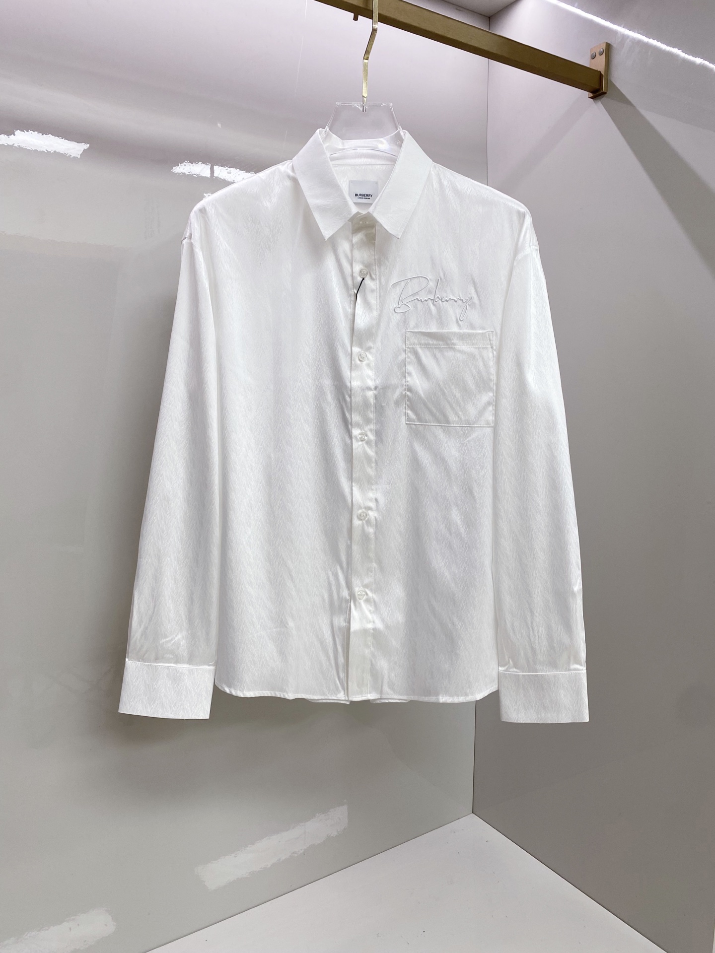 NO:835099,Burberry 2026ss spring and summer dark pattern embroidered shirt  The black/white two-color high-performance new style uses dark jacquard technology and handwritten embroidery to perfectly interpret the British high-end relaxed feeling. High-draping mercerized fabrics are selected, with delicate luster and smooth skin-friendly touch. The upper body is draped and stylish, anti-wrinkle and easy to care for. The body adopts a neat straight shape, with a chest  The handwriting embroidery and dark jacquard details strictly echo each other, injecting brand recognition in a low-key way; the gathered back design optimizes the fit and allows for freedom of movement. Whether worn alone to create a refreshing commuting style, or layered with a suit to create a business elite feel, it can easily create an effortless high-end texture.  Size 48-56,,burberry,burberry,shirts,business suit,19860909Burberry 巴宝莉 2026ss春夏暗纹刺绣衬衫 黑/白双色高能上新,以暗纹提花工艺融合手写体刺绣,完美演绎英伦高阶松弛感.甄选高垂坠丝光面料,自带细腻光泽与顺滑亲肤触感,上身垂坠有型,抗皱易打理.衣身采用利落直筒版型,胸口手写体刺绣与暗纹提花细节严谨呼应,低调注入品牌辨识度；后背收褶设计优化版型,活动自如.无论是单穿打造清爽通勤风,还是叠穿西装演绎商务精英感,都能轻松塑造不费力的高阶质感. 码数48-56,,burberry,burberry,shirts,business suit,,Men's clothing