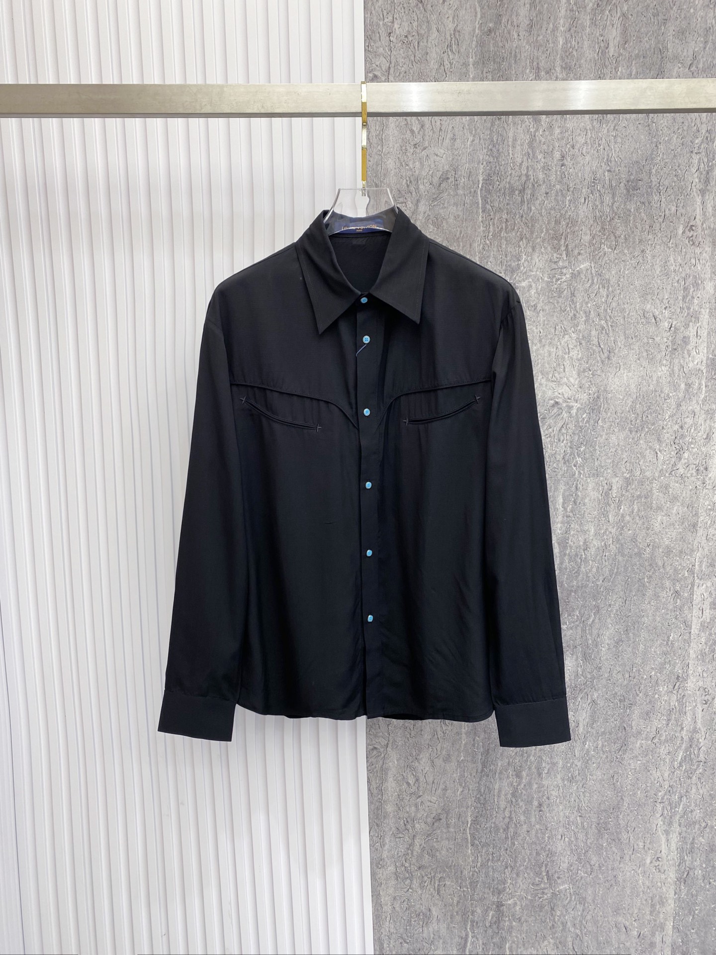 NO:842750,LV  The 2026ss spring and summer limited edition Western-style shirt reconstructs the classic white shirt aesthetic with neat tailoring and clever details. It is made of high-count and high-density poplin fabric, which feels silky and skin-friendly, has a soft light texture, and has a draped and stylish upper body; the body adopts the iconic arc of the Western shirt.  The bust line is divided and decorated with contrasting blue buttons to break the dullness. The curved shoulder design on the back echoes the blue button details on the cuffs. The neat straight silhouette is suitable for a variety of body shapes. Whether worn alone, layered or paired with a suit, it can easily create a relaxed, noble and high-end look.  Size 48-56,,louis vuitton,shirts,business suit,19860909LV 2026ss春夏限定西部风衬衫,以利落剪裁与细节巧思重构经典白衬衫美学.甄选高支高密府绸面料打造,触感丝滑亲肤,自带柔光质感,上身垂坠有型；衣身采用西部衬衫标志性的弧形胸线分割,搭配撞色蓝扣点缀,打破沉闷.后背弧形过肩设计与袖口蓝扣细节呼应,利落直筒版型适配多元身形,无论是单穿、叠穿还是搭配西装,都能轻松塑造松弛显贵的高级感穿搭. 码数48-56,,louis vuitton,shirts,business suit,,Men's clothing