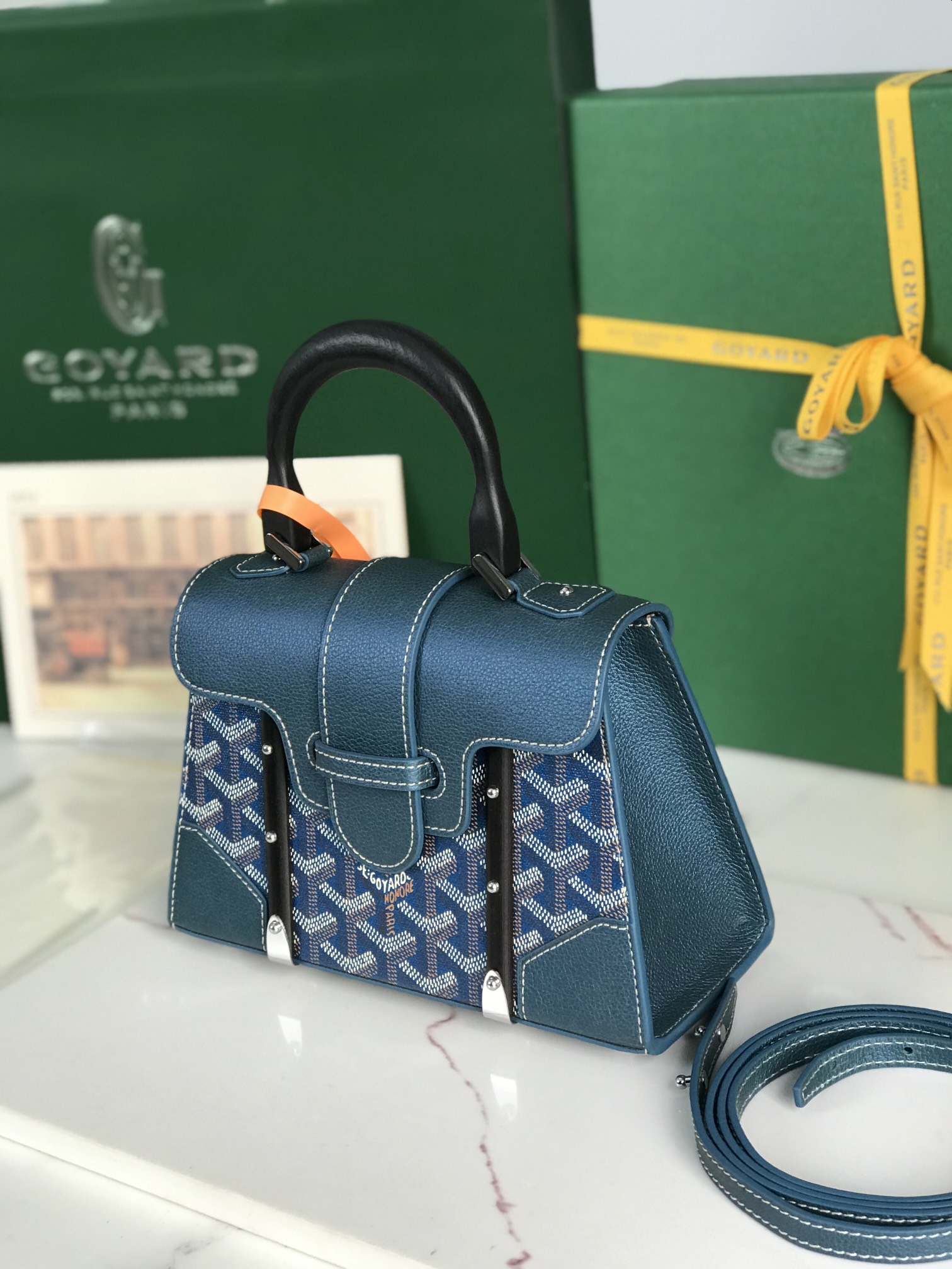p750。💗配原版盒🎁
珠光蓝上新！
Goyard Saïgon包于二十世纪三十年代问世，继推出柔软版Saïgon迷你包后，Goyard推陈出新，坚持对创意的不断追求与突破，塑造了全新结构化的Saïgon迷你包。它与初版Saïgon包的外型一样，拥有简约的几何线条与制箱工艺的细节，以小巧精致的外观唤起Goyard独一无二的优雅魅力及旅行精神。风格经典又符合当代人偏爱使用“小包”的潮流趋势，是匠心之作。可拆卸的皮革肩带能巧妙地转换成三种背法——手提、斜跨和肩背
尺寸size：21*14*8.5cm 
🔎020192