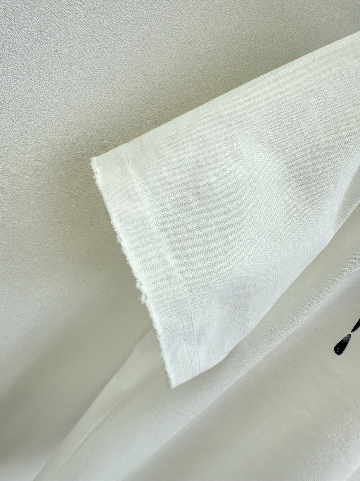 26S B家最新款 简约白T撞上暗黑风泼墨字母，随性又带着点酷感张力。毛边袖口弱化了规整感，松弛感拉满，