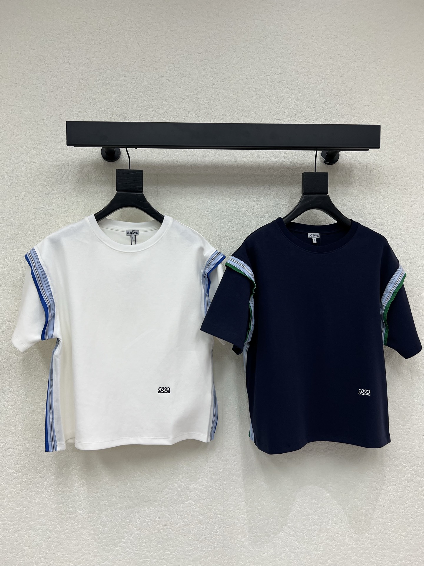 NO:807063,Loew*26 new spring and summer embroidered splicing short-sleeved T-shirt. Based on simplicity, the details are highlighted to give the basic style a high-end texture. The side contrasting webbing splicing is the soul!  The blue and green stripes collide with the solid color body, breaking the monotony and boring, with a sense of visual layering, showing design taste when walking. The low-key embroidered logo on the body is simple but not simple, hiding the brand texture, highlighting the style in the details, refusing to be exaggerated. The classic round neck + loose shoulder design does not pick up the shoulder width, does not block the body shape, and accommodates various body shapes; the drape fabric has a smooth texture, one-click adaptability to commuting, leisure, and light social occasions. SML  A,,loewe,T-shirt,tees,t-shirt,19860909Loew*26春夏新款刺绣拼接短袖T恤.以简约为底,用细节点睛,让基础款穿出高阶质感.侧边撞色织带拼接是灵魂所在！蓝绿条纹与纯色衣身碰撞,打破单调沉闷,自带视觉层次感,行走间尽显设计品味.衣身低调刺绣Logo,简约不简单,暗藏品牌质感,于细微处彰显格调,拒绝浮夸.经典圆领+宽松落肩设计,不挑肩宽、不卡身形,包容各种体态；垂坠面料自带顺滑肌理,通勤、休闲、轻社交场合一键适配.SML A,,loewe,T-shirt,tees，t-shirt,,Women's clothing