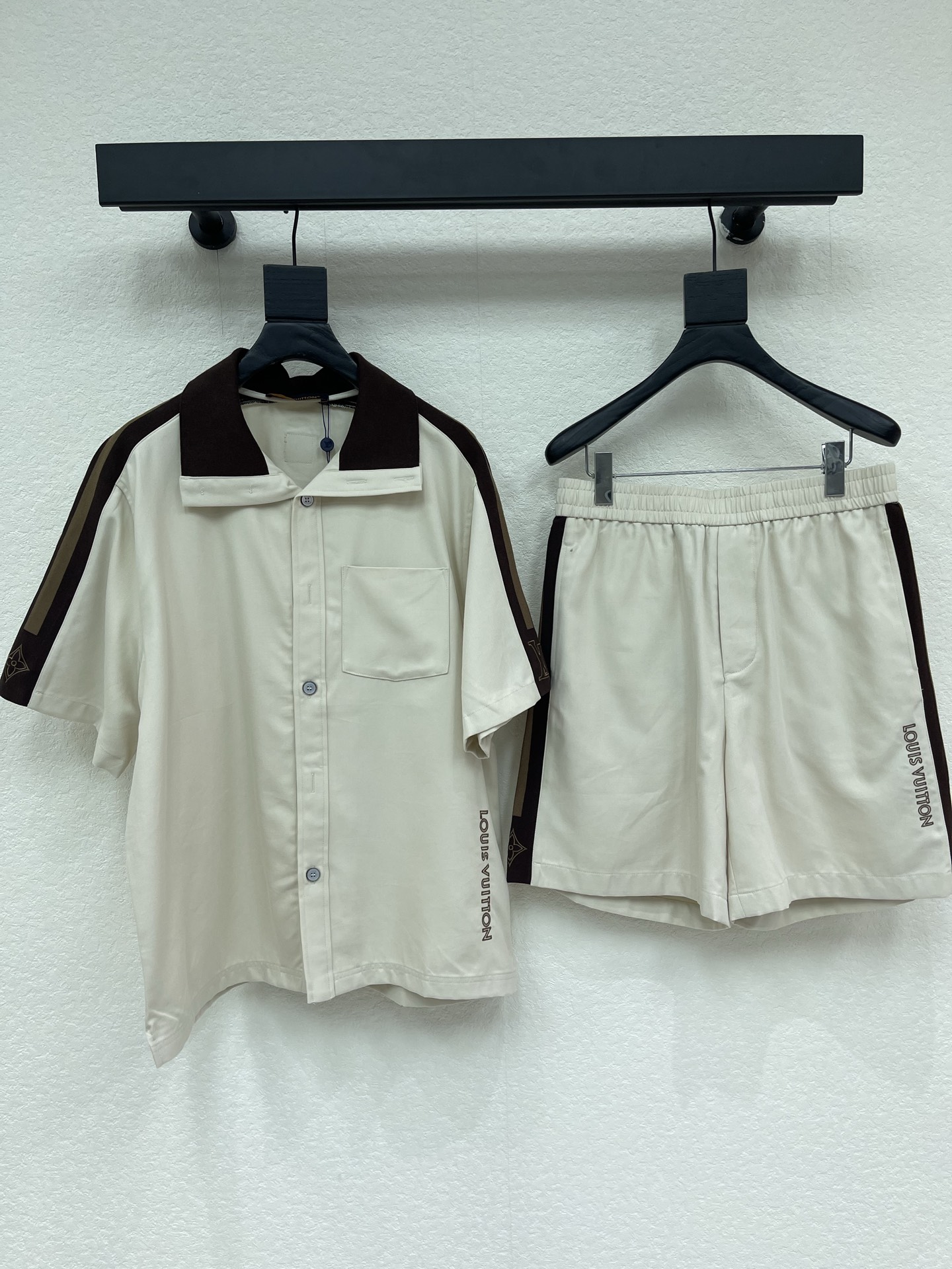 NO:806572,Jacket, shorts, Louis Vuitto*26 new contrasting webbing logo short-sleeved shirt + shorts set. Made of strong drapey acetate Tencel blend fabric, Cuban collar version, the overall is off-white base, the collar is spliced with dark brown contrasting lapels. There are dark brown + khaki contrasting webbing on the side of the sleeves, and the LV logo is embroidered on the cuffs; 'LOUIS VUITTON' is embroidered vertically on the side seam of the body, which is low-key and recognizable.  The front is single-breasted, with a patch pocket on the left chest. The overall cut is loose, and letters are embroidered vertically on the side seams of the trousers, which completely echoes the design language of the shirts of the same series. The embroidery and webbing workmanship is exquisite, and the contrasting color splicing part is neatly routed. It is a representative design of the brand's retro sports style in recent years. The same style for men and women!  One set is detachable!  S-XL,,louis vuitton,louis vuitton,shorts,jackets & coats,shirts,T-shirt,19860909外套 短裤Louis Vuitto*26新款撞色织带标识短袖衬衫+短裤套装.采用垂感强的醋酸 天丝混纺面料,古巴领版型,整体为米白色基底,领部拼接深棕色撞色翻领 袖子侧边有深棕+卡其色的撞色织带,袖口处绣有LV标识；衣身侧缝处竖向刺绣“LOUIS VUITTON”字样,低调又有辨识度. 前襟为单排扣设计,左胸带贴袋,整体剪裁宽松,裤身侧缝竖向刺绣字母,和同系列衬衫的设计语言完全呼应.刺绣和织带工艺精致,撞色拼接部分走线工整,是品牌近年复古运动风的代表性设计.男女同款！ 一套可拆！S-XL,,louis vuitton,louis vuitton,shorts,jackets & coats,shirts,T-shirt,,Women's clothing