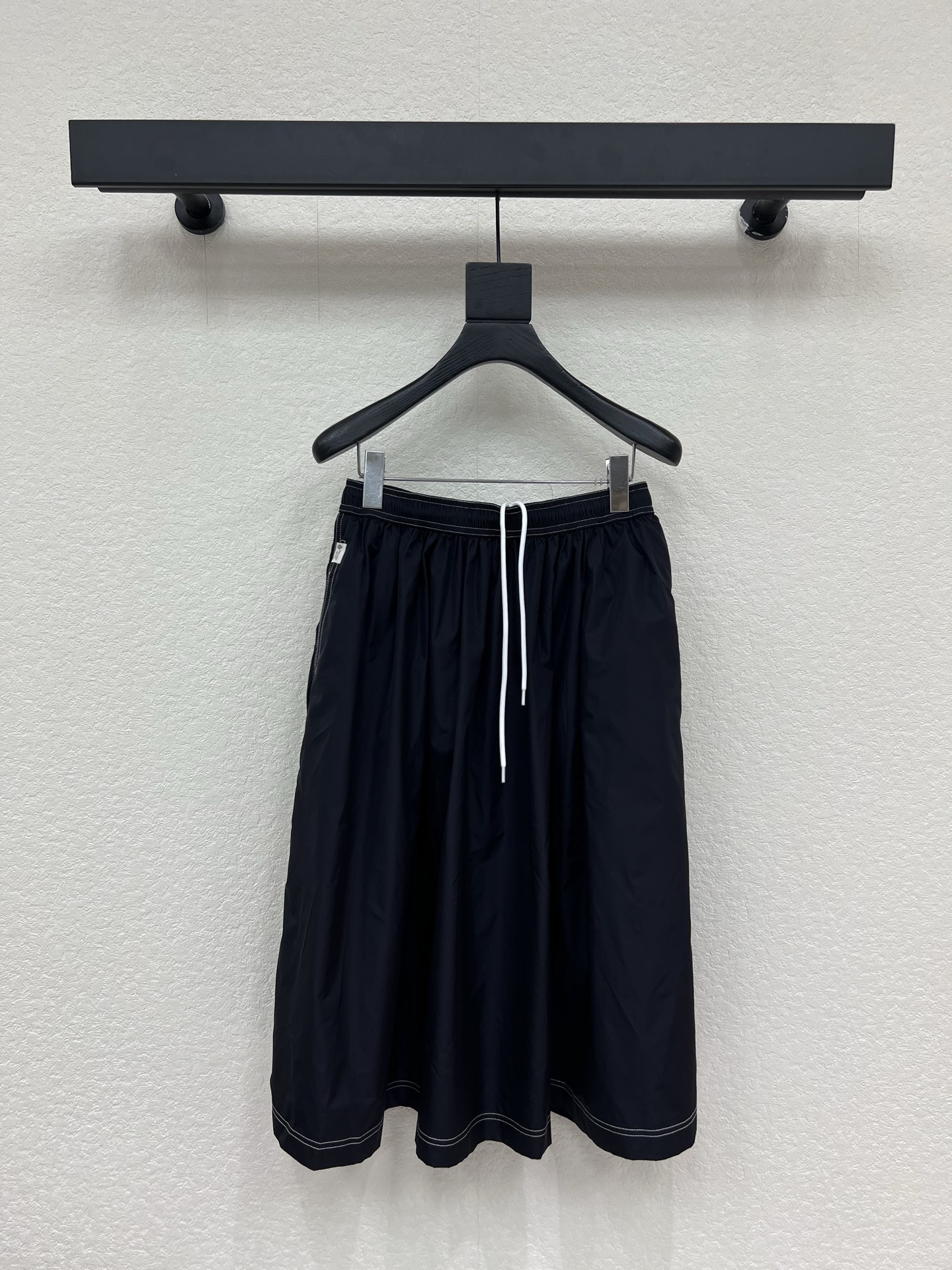 NO:823764,Prad*26 new navy blue nylon A-line skirt. It is made of high-density nylon/blended technical fabric with a soft matte texture. It has drape, wrinkle resistance and slight water-repellent properties. It is light and comfortable to wear. Contrast topstitching technology, drawstring elastic waist design, and small tags on the side pockets with the brand's iconic Solomeo heraldic logo, which low-key highlights the brand identity. It is crisp and stylish. It can support the A-line swing without looking bloated SML  A,,prada,skirts,19860909Prad*26新款藏青色尼龙A字半身裙.采用高密尼龙/混纺科技面料,自带柔和哑光质感,兼具垂坠感、抗皱性与轻微防泼水特性,穿着轻盈舒适.撞色明线工艺,抽绳松紧腰设计,侧袋处的小标签带有品牌标志性的Solomeo纹章徽标,低调彰显品牌身份,挺括有型,既能撑起A字大摆,又不会显得臃肿 SML A,,prada,skirts,,Women's clothing