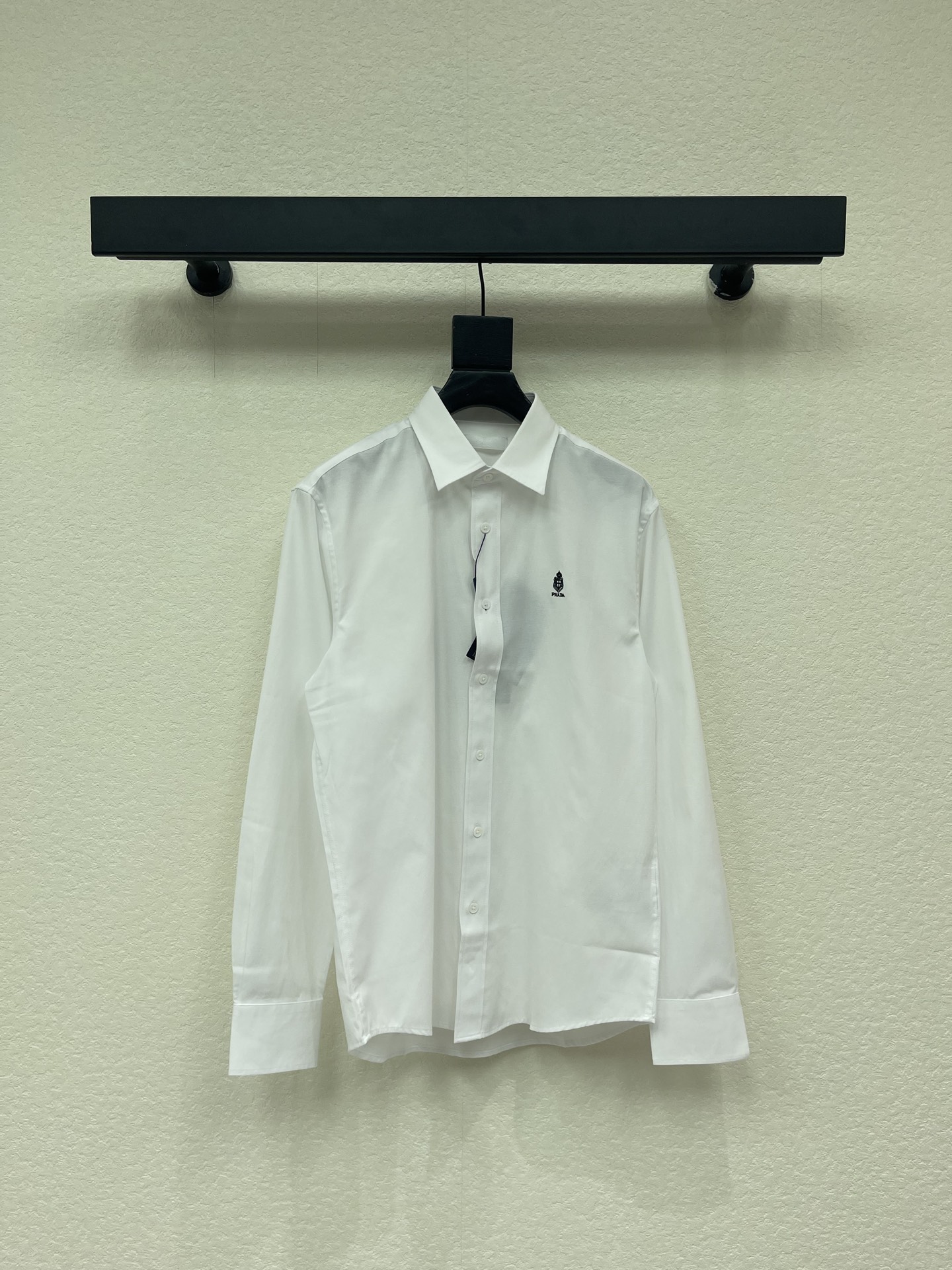 NO:840781,PRAD*26's new classic cotton white shirt is made of high-quality pure cotton. It adopts a classic lapel and long-sleeved cut, with a neat straight silhouette that does not flatter your body shape. It has a single row of mother-of-pearl buttons to open and close, which is warm and delicate. The left chest is decorated with a small embroidered brand logo, which is a low-key identity, and is simple and hidden in recognition. The arc hem and regular cuffs have exquisite details, and the overall shape is neat and elegant, combining the formal feeling of formal wear with the relaxed feeling of casual wear.  The pure white color is versatile and high-end. It can be worn alone to create a relaxed look, or it can be worn under a suit. It is suitable for commuting, business, daily life and other diverse scenarios. It is a luxury brand basic model that combines texture and practicality. Sizes S-2XL, prada, shirts, business suit,19860909PRAD*26新款经典棉质白衬衫,面料甄选优质纯棉,采用经典翻领长袖剪裁,利落直身版型不挑身形；单排珍珠母贝纽扣开合,温润精致；左胸处点缀小巧刺绣品牌徽标,低调标识身份,简约中暗藏辨识度；圆弧下摆、规整袖口细节考究,整体版型利落大气,兼具正装的正式感与休闲的松弛感. 纯白配色百搭高级,可单穿打造松弛感造型,也可内搭西装,适配通勤、商务、日常等多元场景,是兼顾质感与实用性的奢牌基础款. 尺码S-2XL,,prada,shirts,business suit,,Women's clothing
