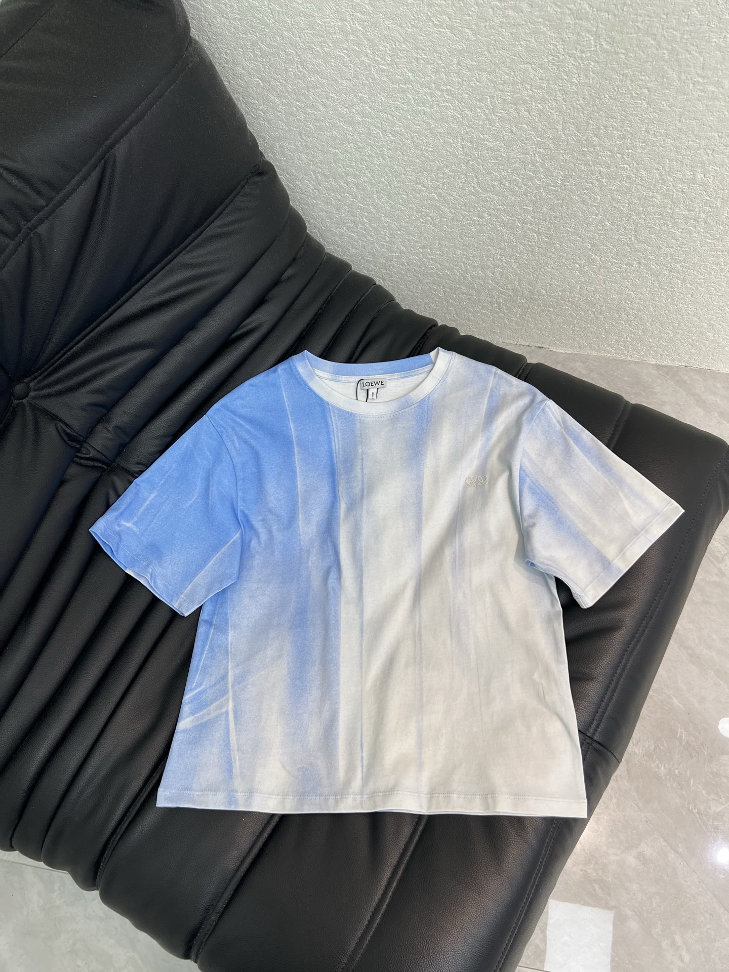 NO:838967,Loew*26 new spring and summer gradient washed short-sleeved T-shirt. Using blue and white blooming as a pen, the gradient texture of the sky and waves is outlined on the pure cotton fabric, bringing a cool and relaxing summer atmosphere. The dropped shoulder silhouette weakens the toughness of the lines, and the chest  The three-dimensional embroidered logo is low-key and injects brand texture. The short length is just suitable for high-waisted bottoms. It is a high-end item that has a breathable feel in daily wear. SML,, loewe, T-shirt, tees, t-shirt,19860909Loew*26春夏新品渐变洗水短袖T恤.以蓝白晕染为笔,在纯棉面料上勾勒出天空与海浪的渐变肌理,自带清冷松弛的夏日氛围.落肩廓形弱化了线条的硬朗,胸前的立体刺绣徽标低调注入品牌质感,短款衣长刚好适配高腰下装,是日常穿搭里自带呼吸感的高级单品.SML,,loewe,T-shirt,tees，t-shirt,,Women's clothing