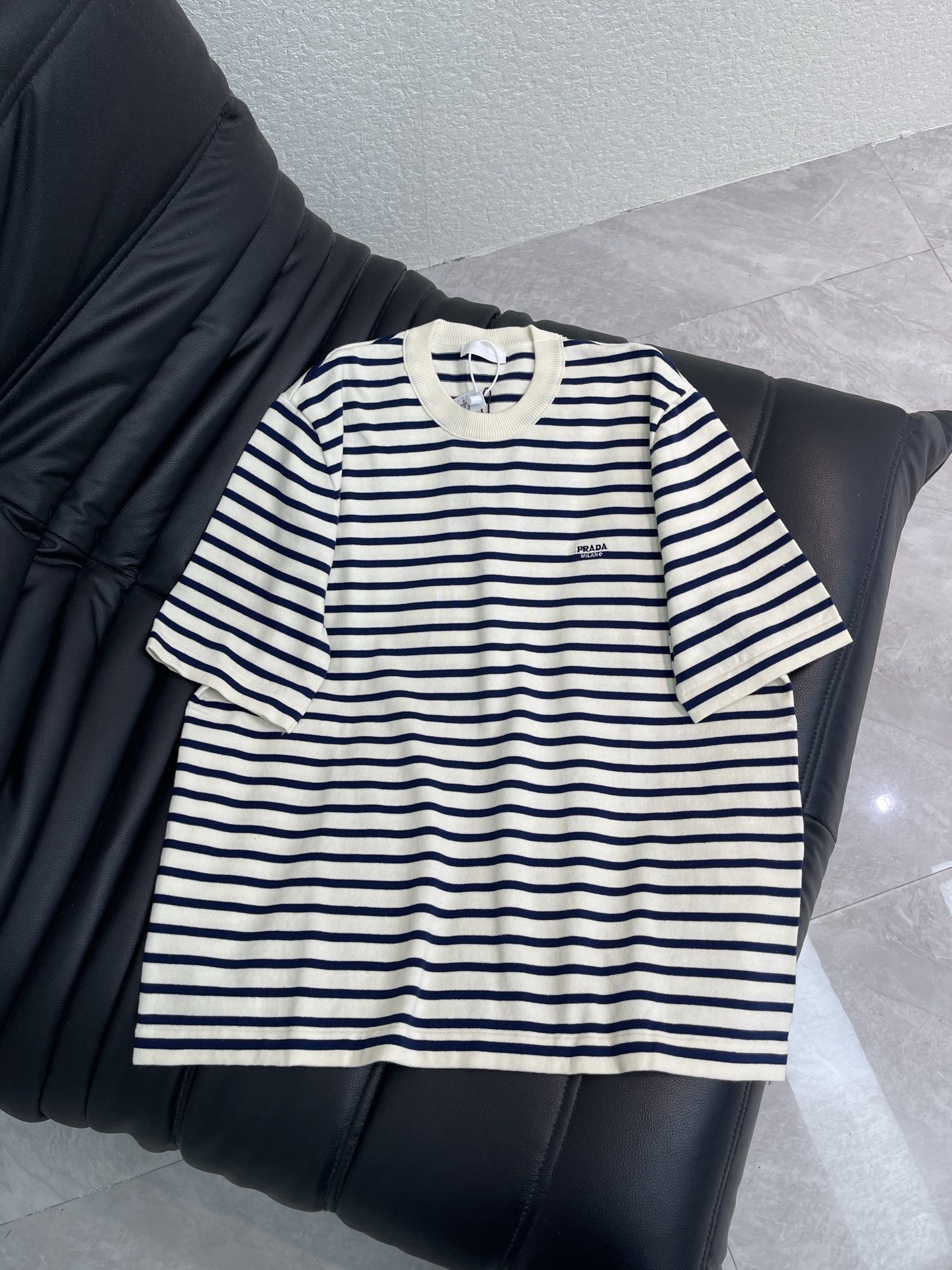 NO:845371,Prad*26 new classic small letter logo embroidered striped knitted short-sleeved T-shirt. Custom-woven mercerized soft cotton knitted fabric, soft, delicate and comfortable against the skin. Soft mist off-white and matte cobalt blue are intertwined in the knitted texture. The iconic P family embroidery hides the logo code between the stripes. It is unobtrusive but weighty enough. It uses the simplest blue and white lines to outline the comfort and elegance of returning to instinct. Imported machine embroidery technology is used, the same style for men and women!  S-XL,,prada,T-shirt,tees,t-shirt,19860909Prad*26新款经典小字母标识刺绣条纹针织短袖T恤.定织丝光柔棉针织料,柔软细腻 舒适贴肤,柔雾米白与哑光钴蓝在针织肌理中交织,标志性P家刺绣隐于条纹间的徽标暗语,不张扬却足够有分量,用最简洁的蓝白线条,勾勒出回归本能的舒适与优雅.采用进口机刺绣工艺,男女同款！S-XL,,prada,T-shirt,tees，t-shirt,,Women's clothing