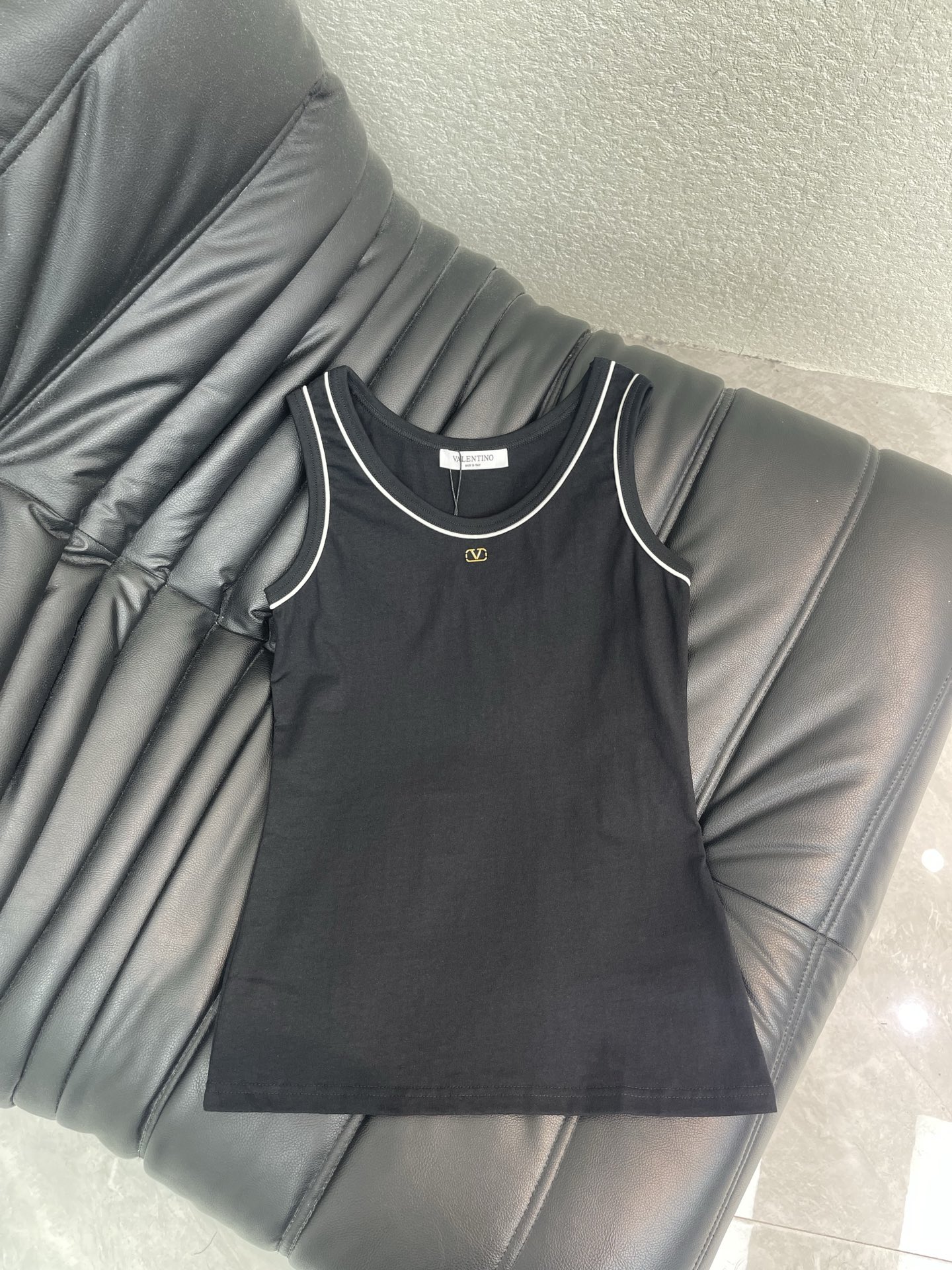 NO:874482,Valentin*26 spring and summer new style vest with contrasting edges and metal logo is a texture that can never go wrong in the wardrobe. Classic black + neat white edges outline the round neck line, and the metal V logo on the chest low-key highlights the brand style. Soft and skin-friendly fabrics fit the body shape, slimming and not tight. The short-sleeved and vest styles are suitable for different scenes. They are neat and noble when worn alone, and can be easily worn when layered to give an effortless sense of luxury. SML, valentino, T-shirt,19860909Valentin*26春夏新款撞色边金属标背心,是衣橱永不出错的质感担当.经典黑色+利落白边勾勒圆领线条,胸口金属V徽标低调彰显品牌格调.软糯亲肤面料贴合身形,修身不紧绷,短袖与背心两款适配不同场景,单穿利落显贵,叠搭也能轻松穿出不费力的高级感.SML,,valentino,T-shirt,,Women's clothing