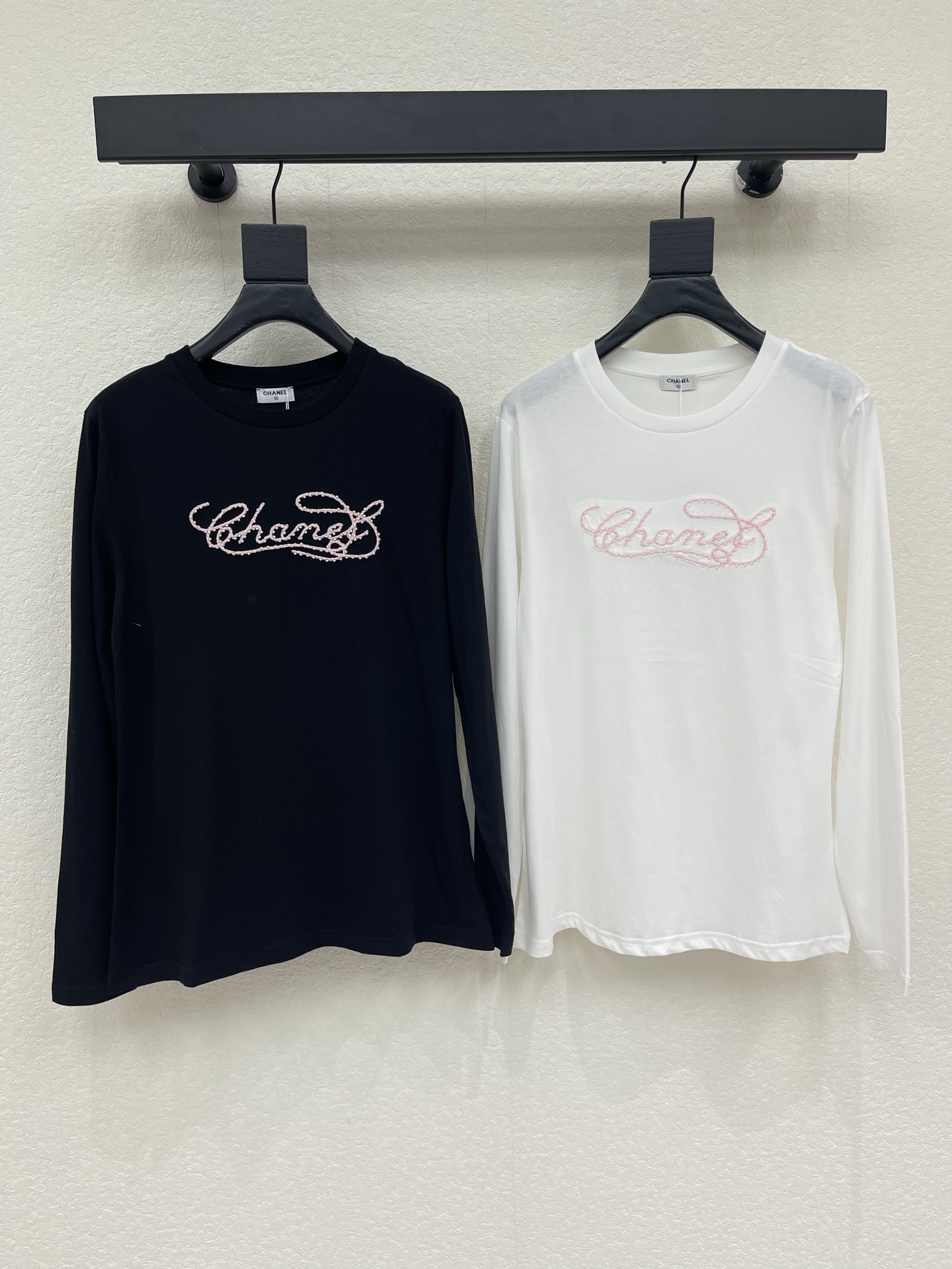 NO:956486,Chane*26 new early autumn embroidered beaded round neck long-sleeved T-shirt, available in black and white classic colors, suitable for different outfits. The round neck style is simple and versatile, the hand-beaded embroidered logo on the chest is exquisite and elegant, and the pink beaded embroidery is gentle and eye-catching, with all the details  Shows ingenuity. The high-elastic, skin-friendly fabric is soft and smooth, and the fit is neat and slim. It can be worn alone to create a simple look, or can be worn under a suit or jacket. It is a practical inner-layer item with a sense of atmosphere that is practical in all seasons. SML,,chanel,jackets  & coats,tees,t-shirt,business suit,19860909Chane*26早秋新品刺绣珠子圆领长袖T恤,黑白经典双色可选,适配不同穿搭调性.圆领版型简约百搭,胸前手工钉珠刺绣logo精致考究,粉色珠绣温柔亮眼,细节尽显匠心.高弹亲肤面料软糯顺滑,合身剪裁利落显瘦,既可单穿打造简约造型,也能内搭西装、外套,是四季都实用的氛围感内搭单品.SML,,chanel,jackets & coats,tees，t-shirt,business suit,,Women's clothing