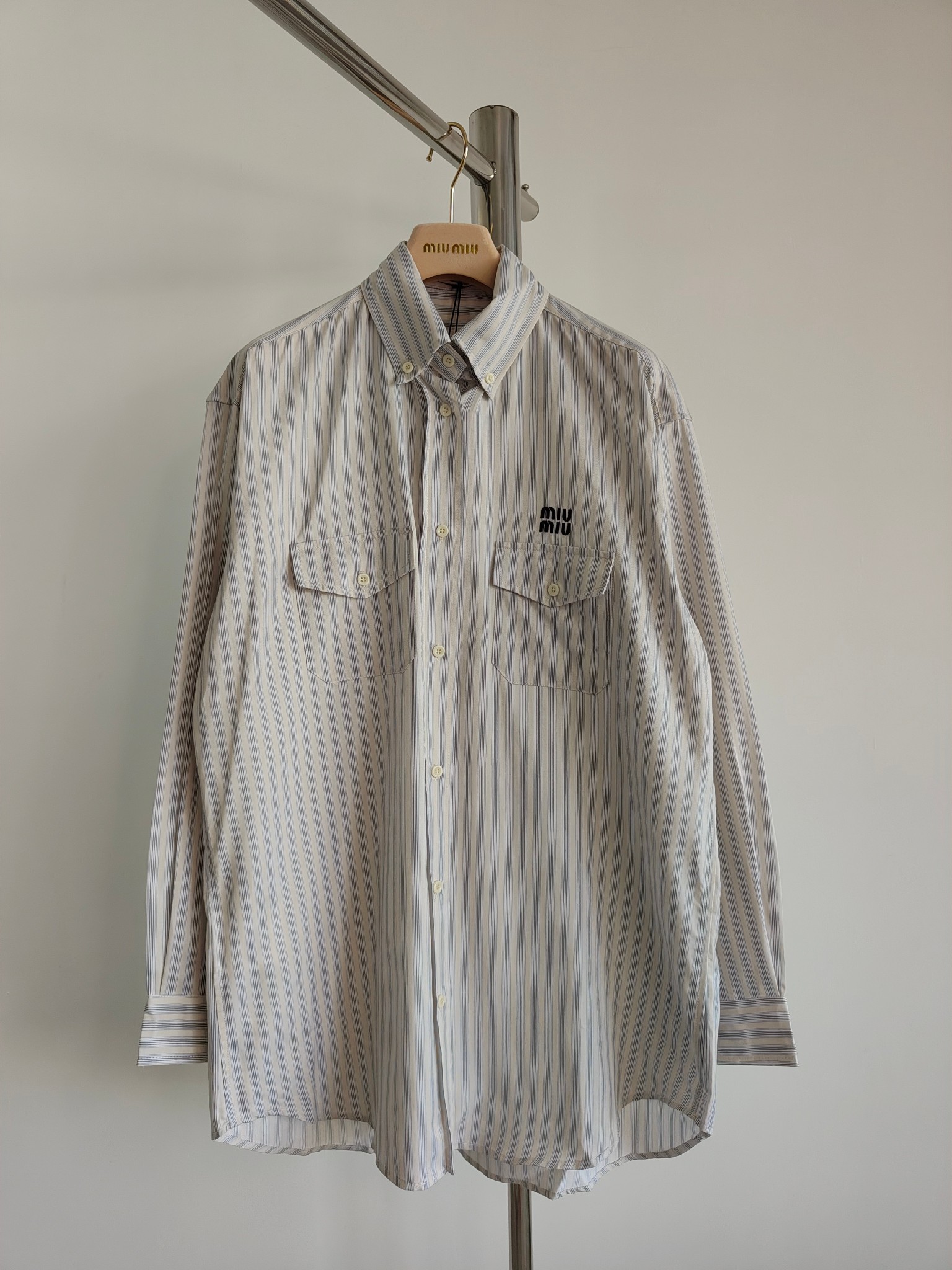 La línea de esta camisa de algodón a rayas se ve más fluida y elegante gracias al bolsillo de solapa Miu y al…