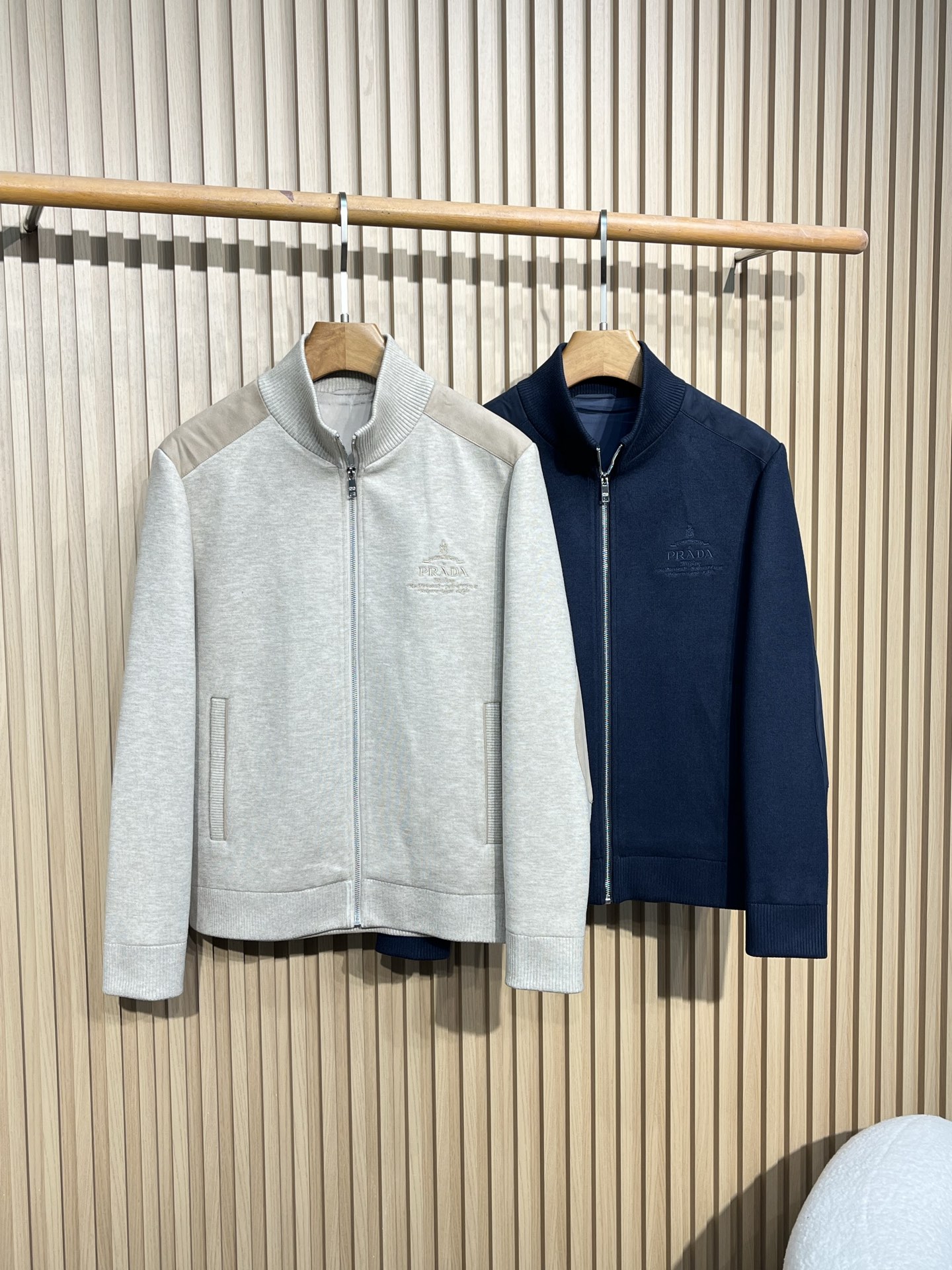 NO:518762,【169】Prada/Prada 2025fw new stand-collar jacket jacket The overall appearance of the zippered stand-collar style, the overall style is casual and business-oriented, classic and versatile, suitable for wearing in various occasions, such as daily travel, office, etc. The two colors are selected as light apricot, giving people a soft, low-key and elegant feeling. The body of the navy blue is navy blue, which looks calm, atmospheric and textured. The fabric composition is taken as an example of the light gray wash mark. The fabric composition includes 61 polyester fiber, 14 nylon, 4 wool, 21 acrylic, and the blend of various fibers makes the fabric both crisp, wear-resistant and warm. The lining is polyester fiber, which is smooth and comfortable, making it easy to put on and take off. The fabric presents a knitted texture, with a delicate surface, and is comfortable to wear.  The collars are designed with rib knit stand collars, which fit the neck, keep warm and modify the neck lines, increasing the three-dimensional feeling when worn, and also showing a capable style. The cuffs and hem are used to use rib knit, which echoes the neckline, plays a tightening role, effectively preventing cold air from pouring in, and shaping a neat outline. The zipper zipper head has a brand-related logo, reflecting the brand details, and the zipper texture is good, and the opening and closing is smooth. Elbow patches have oval patches at the elbows. The light gray patches are light beige, and the navy blue patches are dark blue. The patch material is different from the main fabric. The leather increases the design sense and practicality, which can prevent excessive wear of the elbows. There is a delicate Prada embroidered brand logo on the chest, with delicate fonts and patterns, demonstrating the brand identity;  There is a small triangle logo under the collar on the back, which may also be a brand logo element. 48: Shoulder width 44 Bust 110 Clothes length 63 Sleeve length 60 50: Shoulder width 45 Bust 114 Clothes length 64 Sleeve length 61 52: Shoulder width 46 Bust 118 Clothes length 65 Sleeve length 62 54: Shoulder width 57 Bust 122 Clothes length 66 Sleeve length 63 56: Shoulder width 58 Bust 126 Clothes length 67 Sleeve length 64,,prada,prada,jackets & coats,alexander wang19860909【169】Prada/普拉达 2025fw新款立领茄克外套 整体外观拉链开合的立领款式,整体风格偏向休闲商务,经典百搭,适合多种场合穿着,比如日常出行、办公等 . 两个颜色选择浅杏色款主体为浅杏色,给人一种柔和、低调且优雅的感觉. 藏蓝色款主体为藏蓝色,显得沉稳、大气且富有质感 . 面料成分以浅灰色款水洗标为例,面料成分包含61聚酯纤维、14锦纶 、4羊毛、21腈纶,多种纤维混纺使得面料兼具挺括性、耐磨性和一定的保暖性；里料为聚酯纤维,顺滑舒适,便于穿脱. 面料呈现出针织质感,表面较为细腻,贴身穿着舒适. 领口均采用罗纹针织立领设计,贴合颈部,保暖的同时可以修饰颈部线条,增加穿着时的立体感,同时也展现出干练的风格. 袖口和下摆使用罗纹针织,与领口相呼应,起到收紧作用,能有效防止冷风灌入,同时塑造利落的穿着轮廓. 拉链拉链头上有品牌相关标识,体现品牌细节,且拉链质感良好,开合顺滑. 肘部补丁两款外套的肘部位置都有椭圆形的补丁设计,浅灰色款补丁为浅米色,藏蓝色款补丁为深蓝色,补丁材质与主体面料不同,皮质增加了设计感和实用性,可以防止肘部位置过度磨损. 胸前有精致的Prada刺绣品牌标识,字体和图案细腻,彰显品牌身份； 背部领口下方有一个小的三角形标识,可能也是品牌标志元素. 48:肩宽44 胸围110 衣长63 袖长60 50:肩宽45 胸围114 衣长64 袖长61 52:肩宽46 胸围118 衣长65 袖长62 54:肩宽57 胸围122 衣长66 袖长63 56:肩宽58 胸围126 衣长67 袖长64,,prada,prada,jackets & coats,alexander wang,Men's clothing