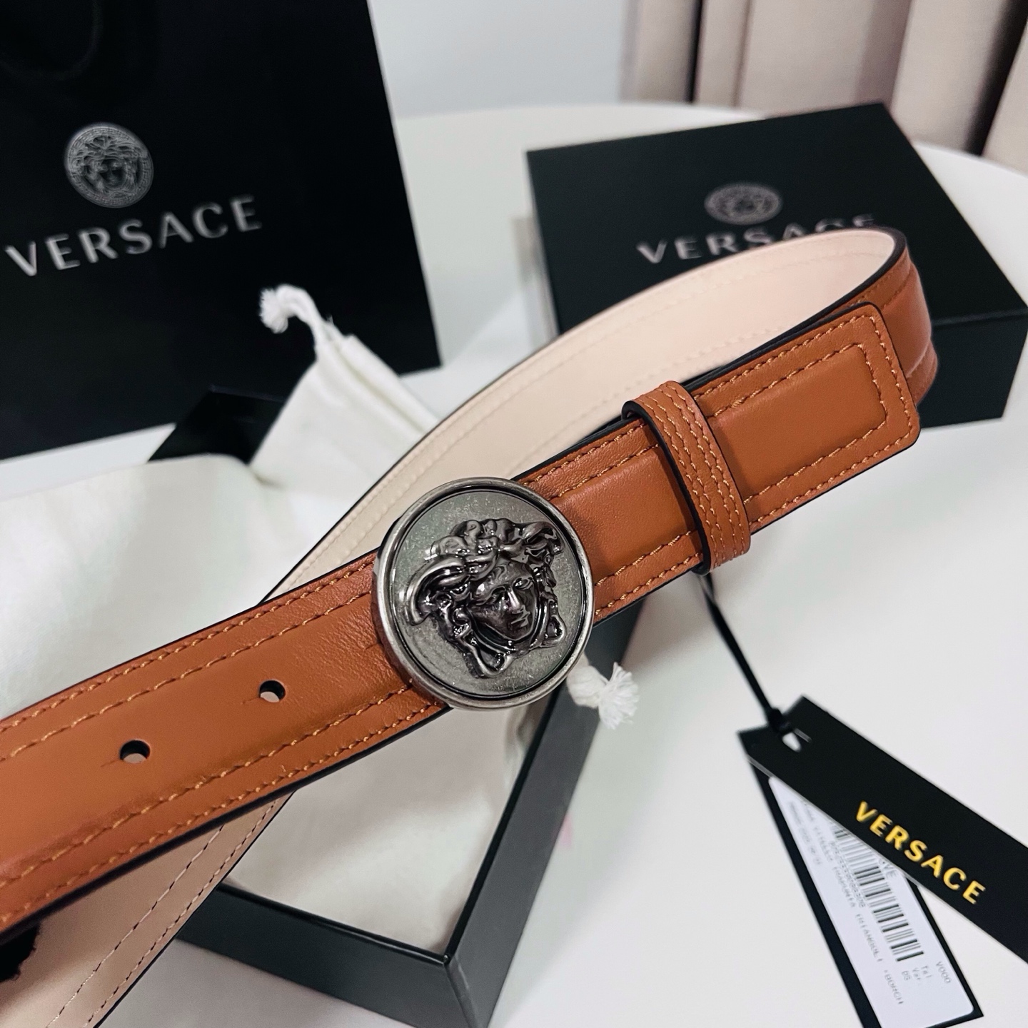 范思哲，新款牛皮革腰带，饰有Versace Logo字样，配有圆形金属搭扣，搭扣采用复古饰面，镶嵌立体M