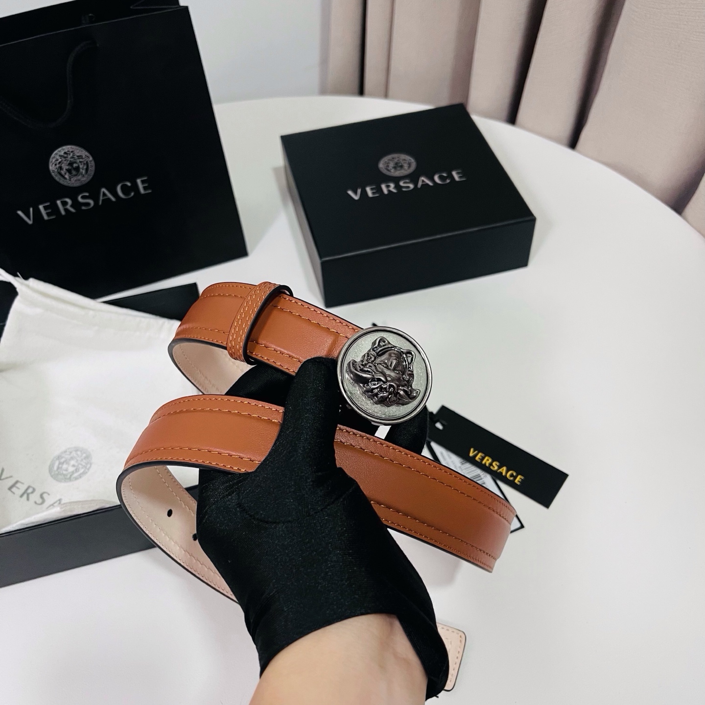 范思哲，新款牛皮革腰带，饰有Versace Logo字样，配有圆形金属搭扣，搭扣采用复古饰面，镶嵌立体M