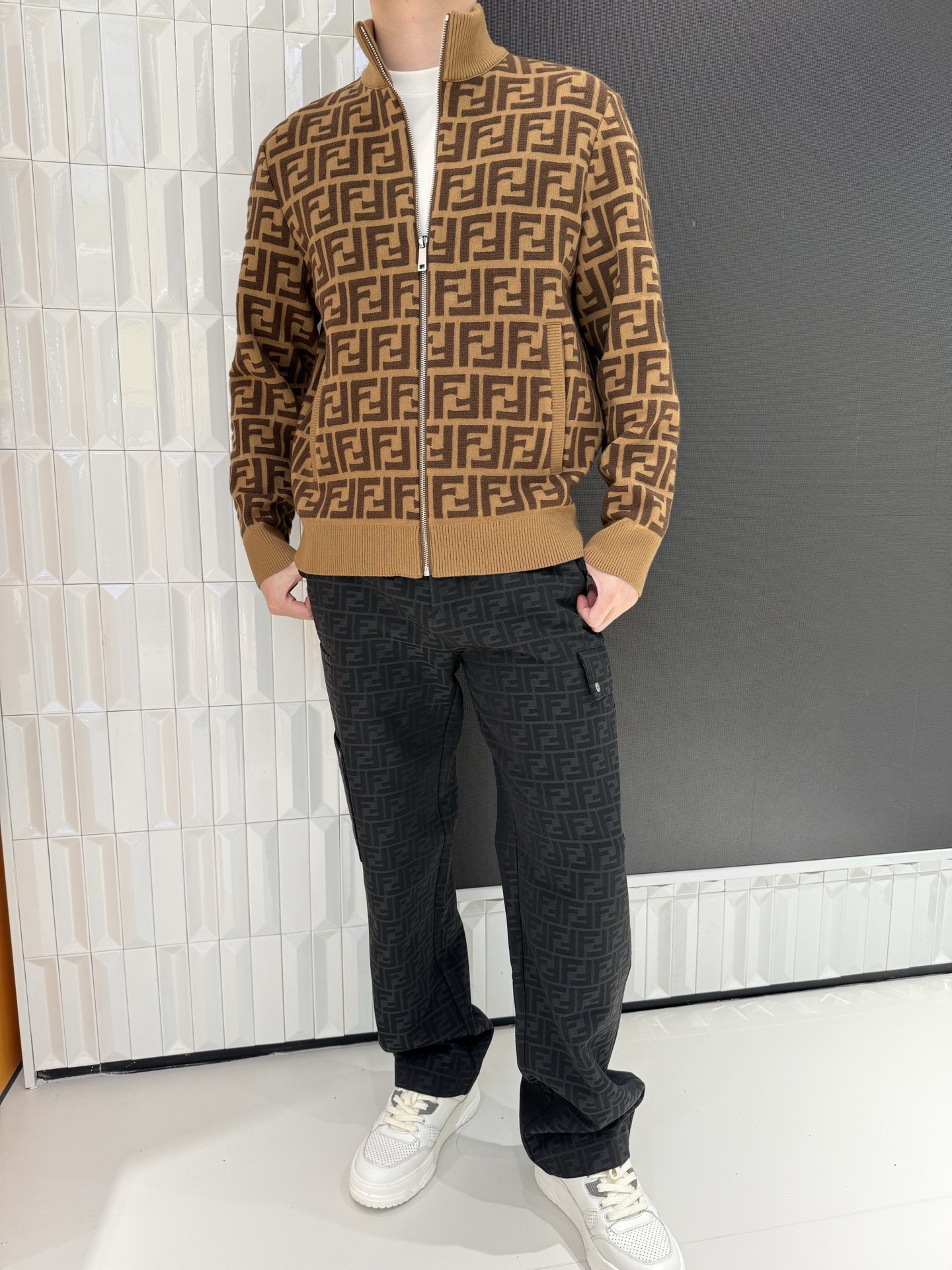 NO:691292,Fendi  The knitted cardigan is designed with classic double F presbyopia all-over jacquard as the core design. The color combination of caramel brown and dark brown shows a retro charm and is highly recognizable visually. Made of high-quality knitted fabric, it feels soft, skin-friendly and elastic, taking into account warmth and wearing comfort; the stand-up collar zipper version is neat and stylish  , the zipper can be freely adjusted to create a high-necked windproof look, or can be half-opened to create a casual and casual look. The ribbed cuffs and hem further fit the body shape. Pair it with the same series of presbyopic trousers or a simple white T-shirt to easily unlock high-end light luxury wear. It is a versatile core item for your autumn and winter wardrobe.  Size 48-56 (model is 180cm tall and weighs 140cm, wearing size 50),,fendi,19860909芬迪 针织开衫以经典双F老花满印提花为核心设计,焦糖棕与深棕的配色尽显复古韵味,视觉上极具辨识度.采用高品质针织面料打造,触感软糯亲肤且富有弹性,兼顾保暖性与穿着舒适度；立领拉链版型利落有型,拉链可自由调节开合度,既能打造高领防风造型,也能半开营造随性休闲感.罗纹收边的袖口与下摆进一步贴合身形,搭配同系列老花裤装或简约白T,轻松解锁高阶轻奢穿搭,是秋冬衣橱的百搭核心单品. 48-56码（模特身高180体重140穿50码）,,fendi,,Men's clothing