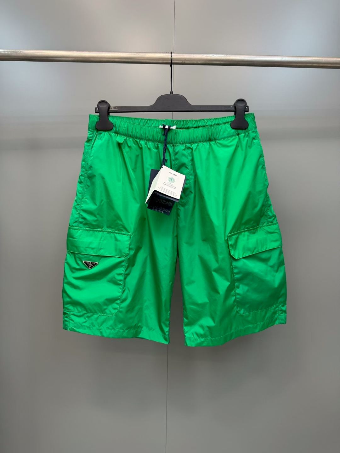 NO:852942,PRA metal triangle logo nylon cargo shorts  It is made of imported regenerated nylon fabric and has been treated with multiple waterproof, splash-proof and anti-wrinkle processes. The texture is light and smooth, with a cool and crisp touch. It has excellent breathability, drape and anti-deformation properties. It is not easy to wrinkle and collapse after long-term wear. The upper body is refreshing and comfortable with a sense of coolness; the waistband adopts a wide-edge high-density elastic design, with hidden  The drawstrings are adjustable to fit the waist line, neither tight nor loose, and are casual and comfortable. The tightness can be adjusted freely while ensuring the neatness of the overall line. The trouser legs are made of precision double stitching technology, which ensures even and smooth alignment. The hemming is firm and comfortable, and does not pinch the skin when worn. The fabric has built-in anti-UV properties and is both practical and functional.  Material: nylon, loose fit, color military green/black/khaki, size S/M/L/XL, Prada-clothing, prada, prada, shorts,19860909PRA金属三角标尼龙工装短裤 采用进口再生尼龙面料,经过多道防水防泼与抗皱工艺处理,质地轻薄顺滑,触感凉润挺括,兼具优异的透气性、垂坠感与抗变形性能,久穿不易起皱软塌,上身清爽舒适自带凉感；腰头采用宽边高密松紧设计,搭配隐形抽绳调节,贴合腰部线条,不勒不松,随性舒适,既能自由调节松紧度又保证整体线条的利落感；裤脚采用精密双车线工艺,走线均匀平整,锁边牢固舒适,穿着不勒肤；面料自带抗紫外线属性,兼具实用性与机能感. 材质: 锦纶 版型宽松 颜色军绿/黑色/卡其 尺码S/M/L/XL,普拉达-服装,prada,prada,shorts,,Women's clothing